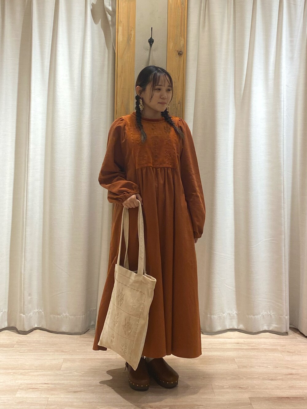 オレンジ系のワンピース、ベージュ系のハンドバッグを着用したレディースの夏コーディネートの3枚目の写真