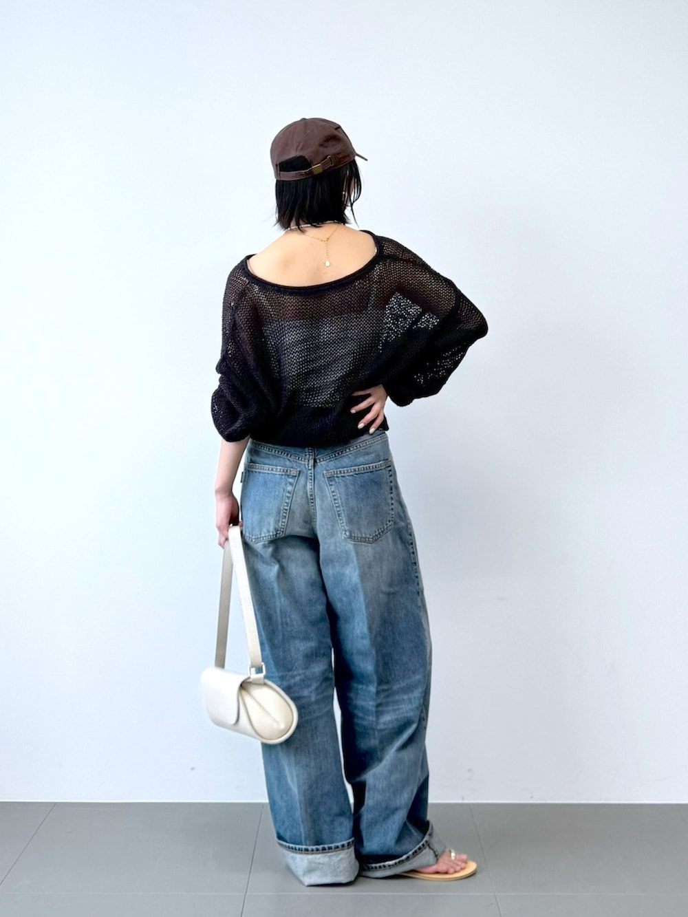 ブルー系のデニムパンツ、ホワイト系のショルダーバッグ、ホワイト系のキャミソールを着用したレディースの春コーディネートの4枚目の写真