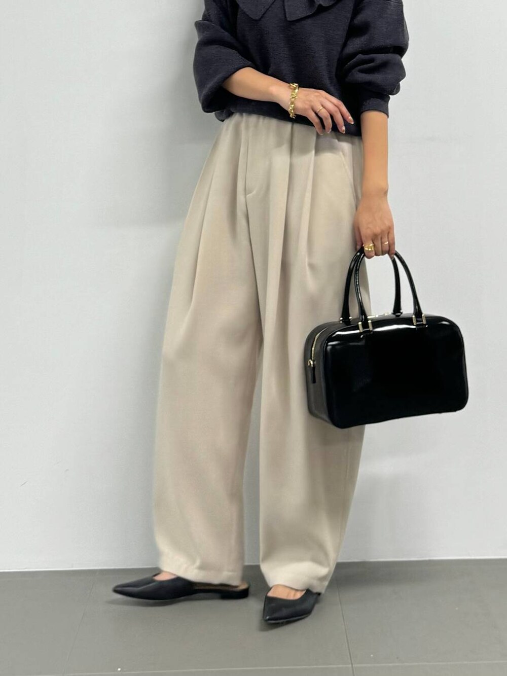 ブラック系のボストンバッグ、ブラック系のパンプス、グレー系のニット/セーターを着用したレディースの秋コーディネートの6枚目の写真