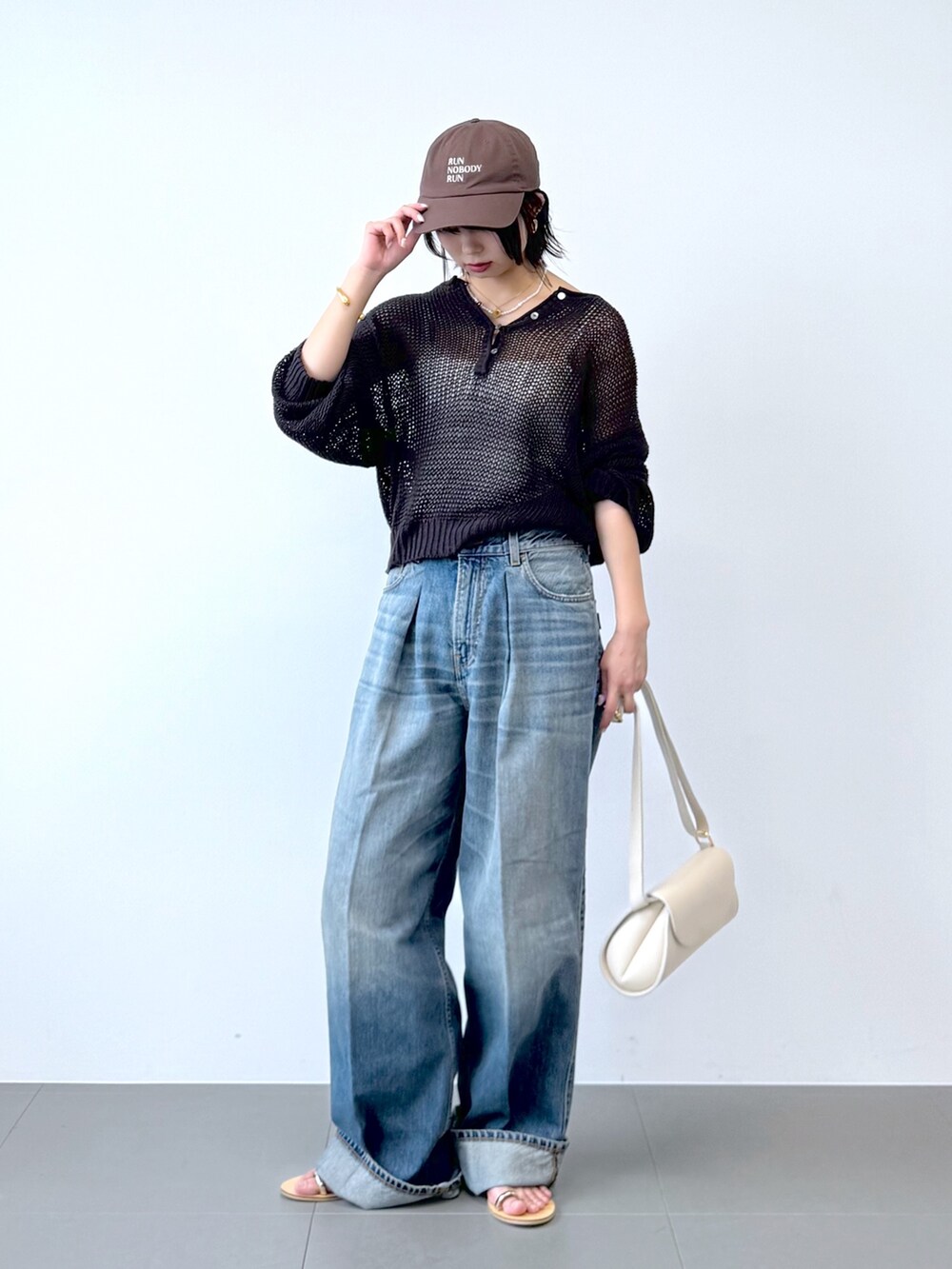 ブルー系のデニムパンツ、ホワイト系のショルダーバッグ、ホワイト系のキャミソールを着用したレディースの春コーディネートの5枚目の写真