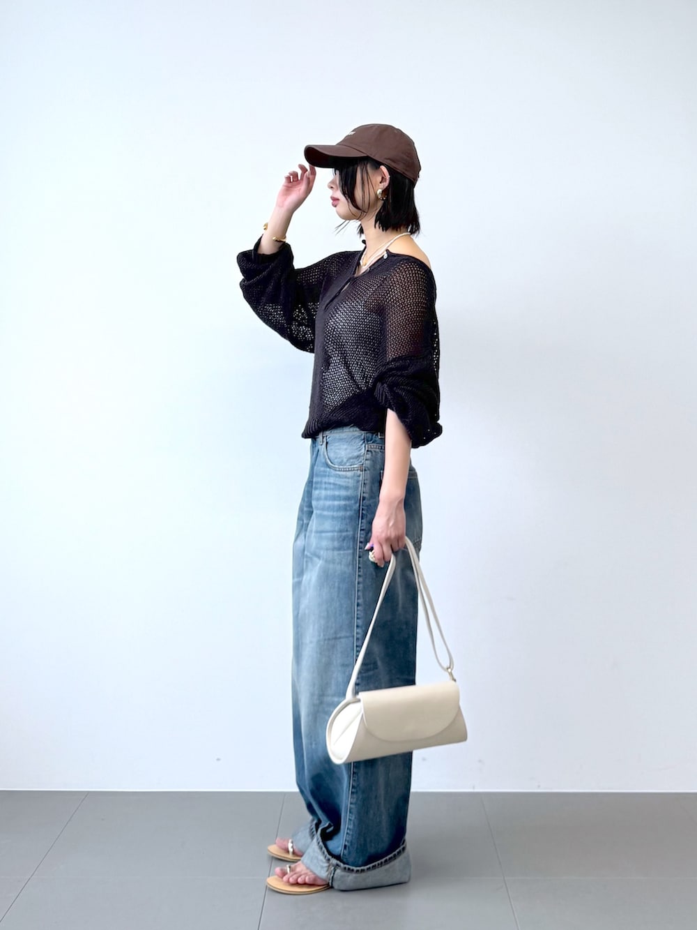 ブルー系のデニムパンツ、ホワイト系のショルダーバッグ、ホワイト系のキャミソールを着用したレディースの春コーディネートの3枚目の写真
