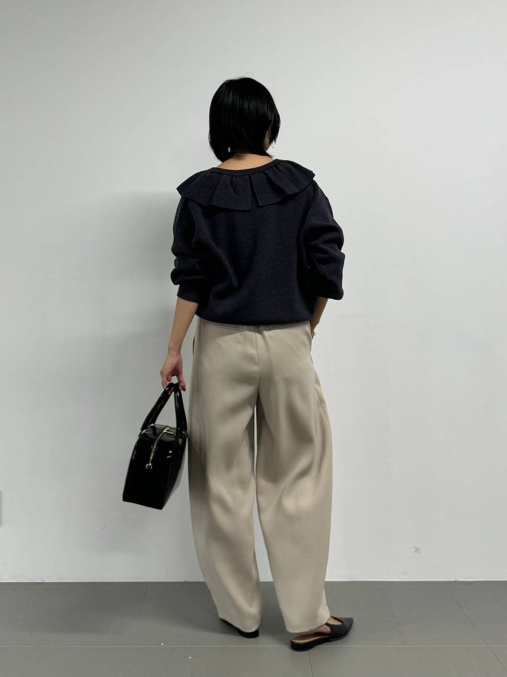 ブラック系のボストンバッグ、ブラック系のパンプス、グレー系のニット/セーターを着用したレディースの秋コーディネートの3枚目の写真
