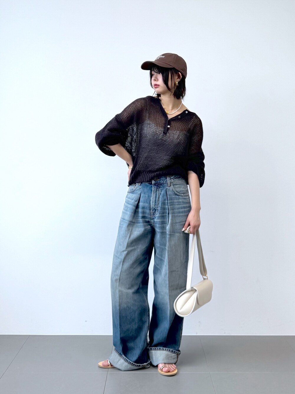ブルー系のデニムパンツ、ホワイト系のショルダーバッグ、ホワイト系のキャミソールを着用したレディースの春コーディネートの2枚目の写真