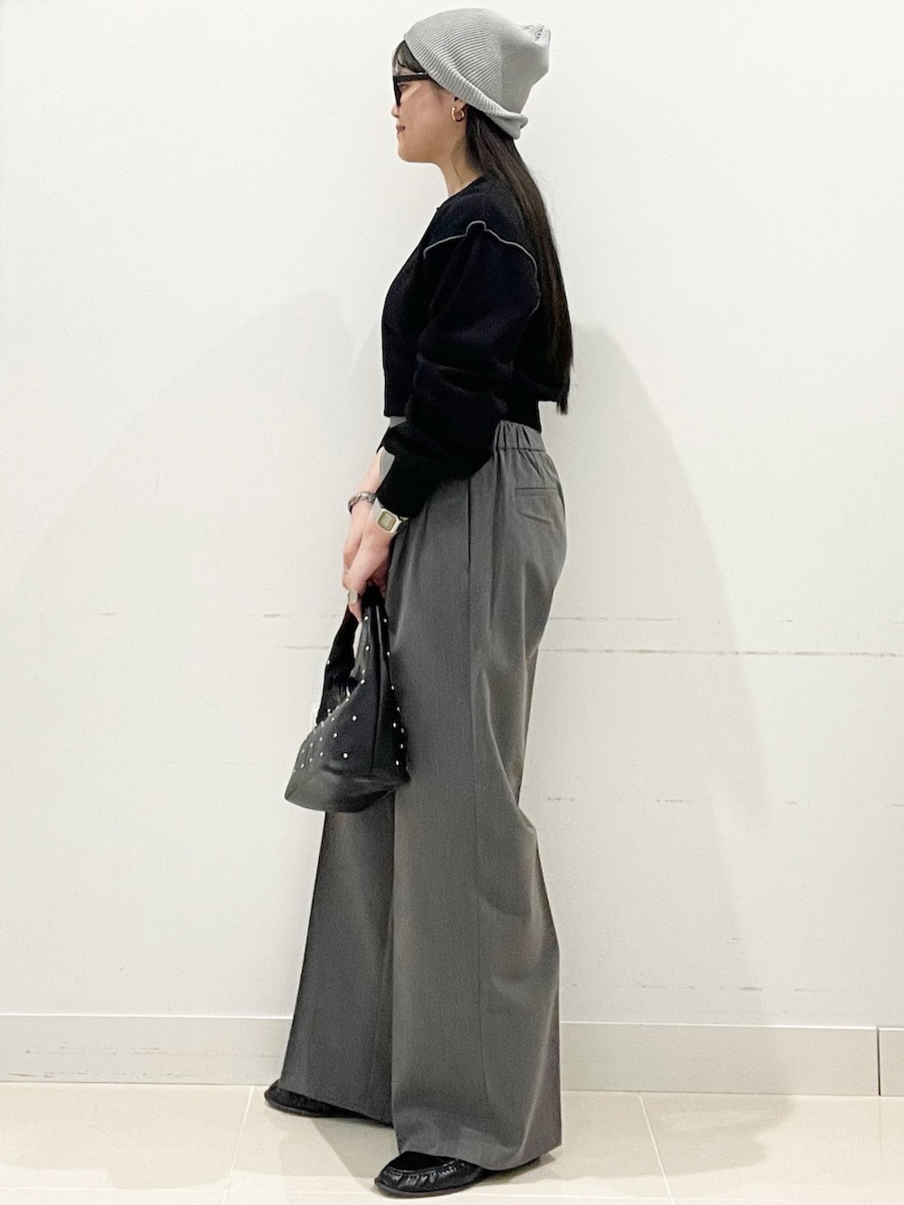グレー系のスラックス、ブラック系のハンドバッグ、ブラック系のスウェットを着用したレディースの春コーディネートの5枚目の写真