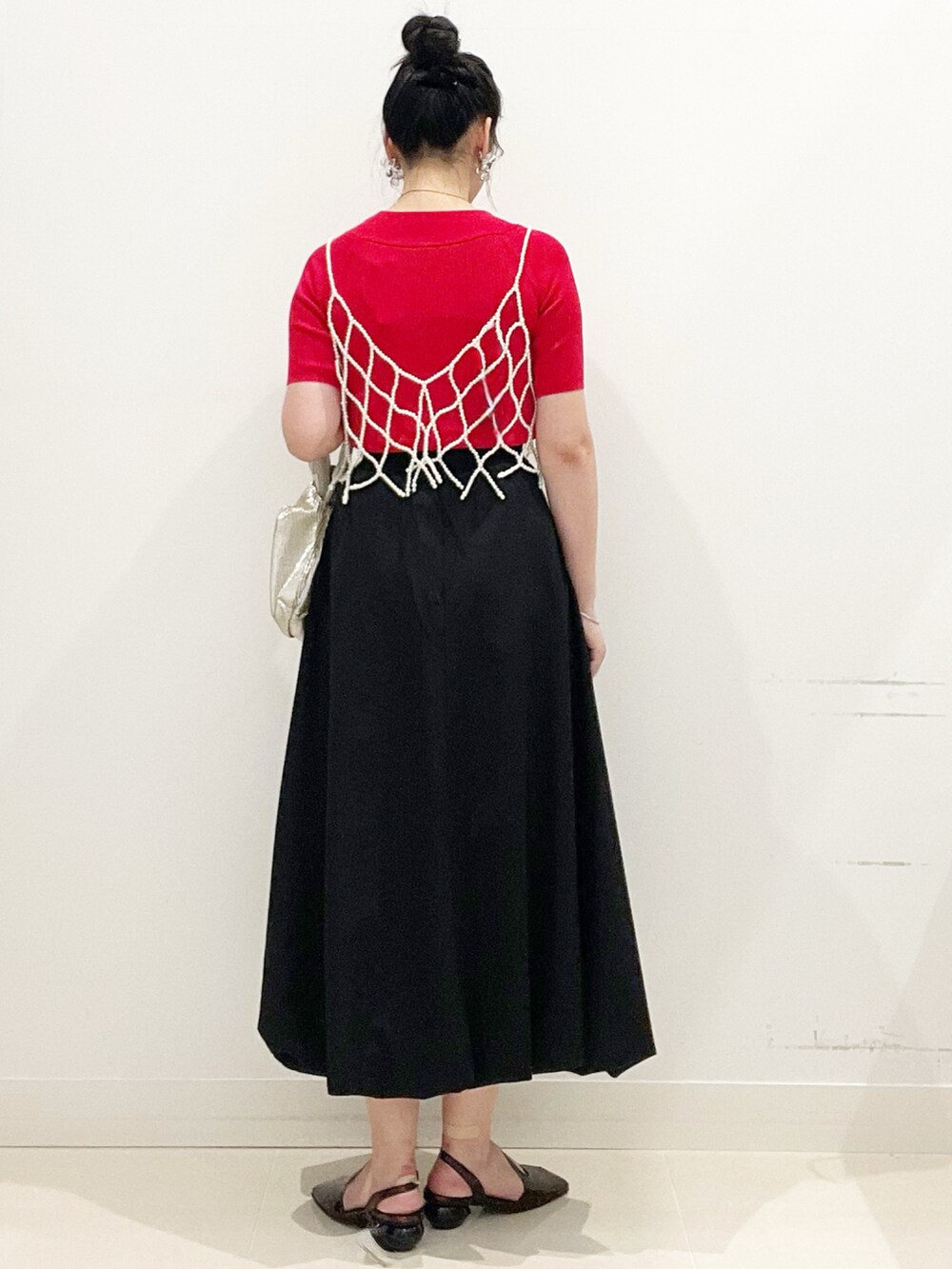 ブラック系のスカート、ゴールド系のハンドバッグ、レッド系のニット/セーターを着用したレディースの夏コーディネートの7枚目の写真