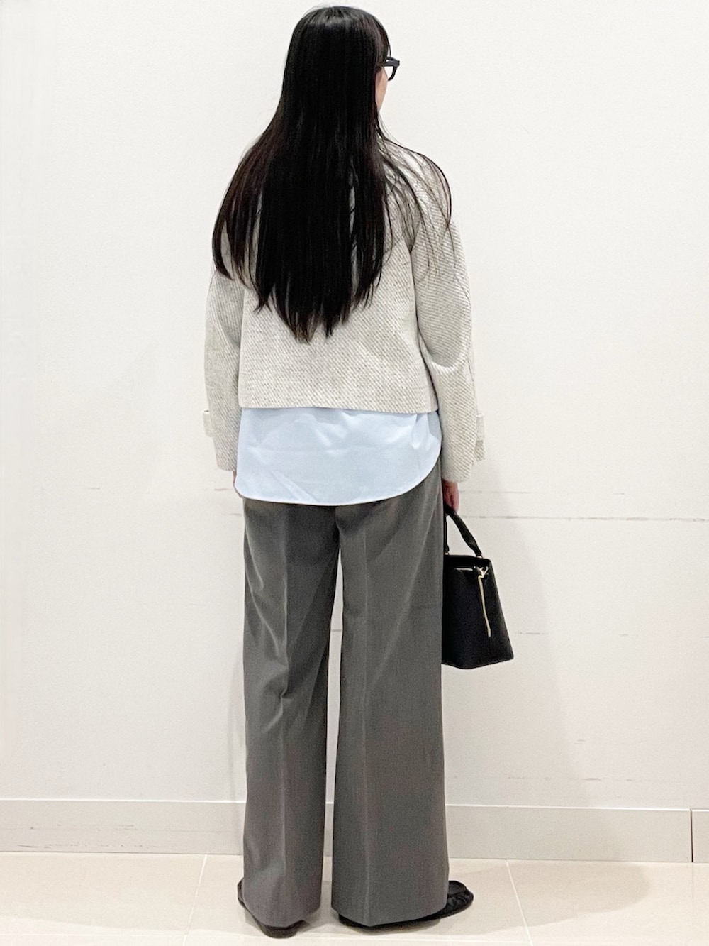 グレー系のスラックス、ブラック系のハンドバッグ、ブルー系のシャツ/ブラウスを着用したレディースの春コーディネートの5枚目の写真
