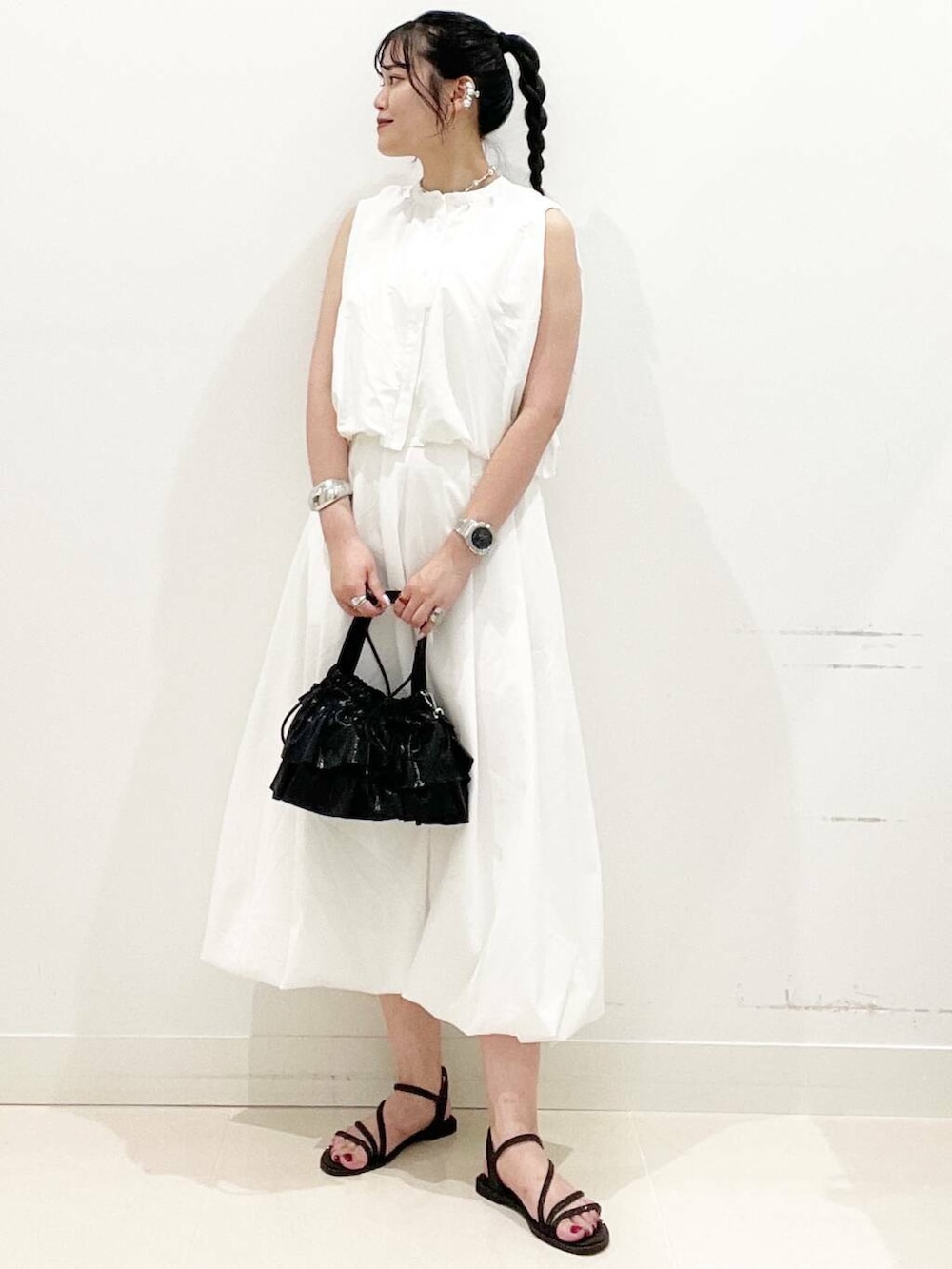 ブラック系のショルダーバッグ、ホワイト系のスカート、ホワイト系のキャミソールを着用したレディースの夏コーディネートの2枚目の写真