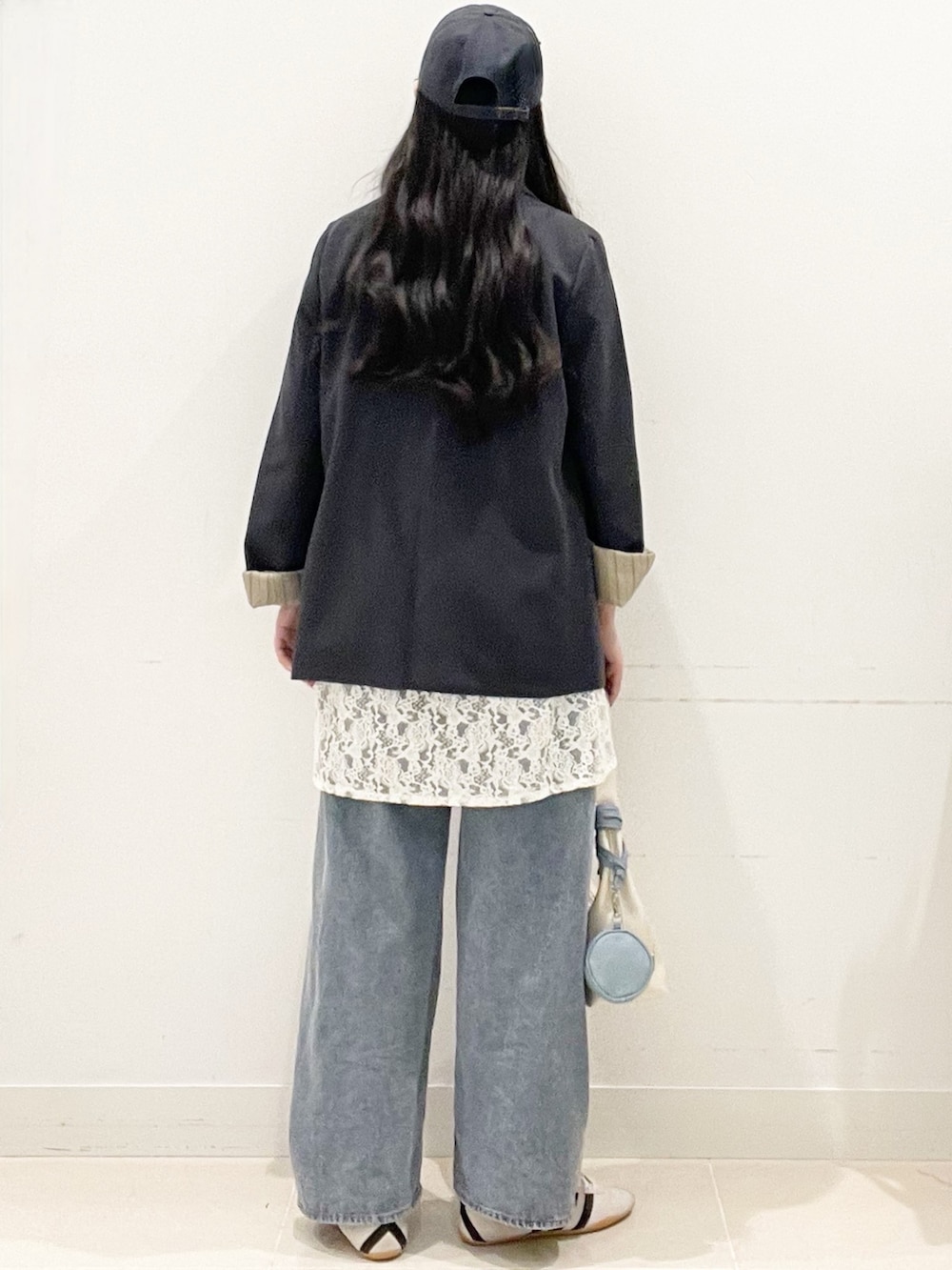 ホワイト系のスニーカー、ブルー系のデニムパンツ、ホワイト系のキャミソールを着用したレディースの春コーディネートの4枚目の写真