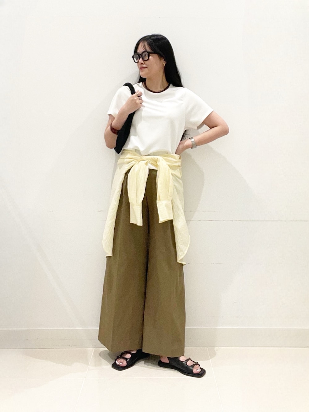 ベージュ系のチノパンツ、ブラック系のサンダル、イエロー系のシャツ/ブラウスを着用したレディースの夏コーディネートの2枚目の写真