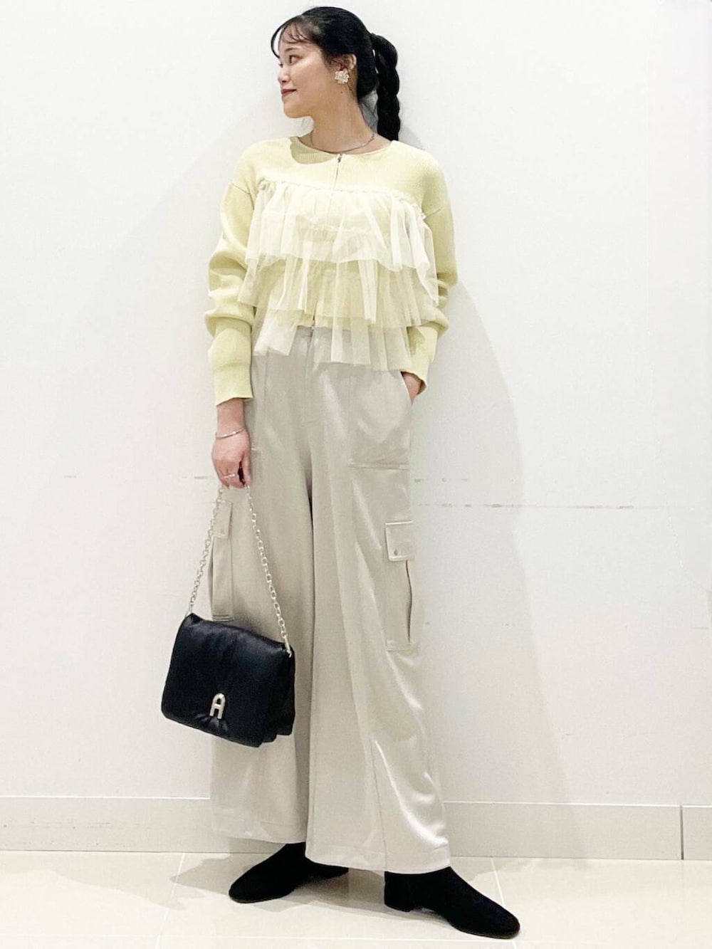 ブラック系のブーツ、ブラック系のショルダーバッグ、イエロー系のニット/セーターを着用したレディースの冬コーディネートの4枚目の写真