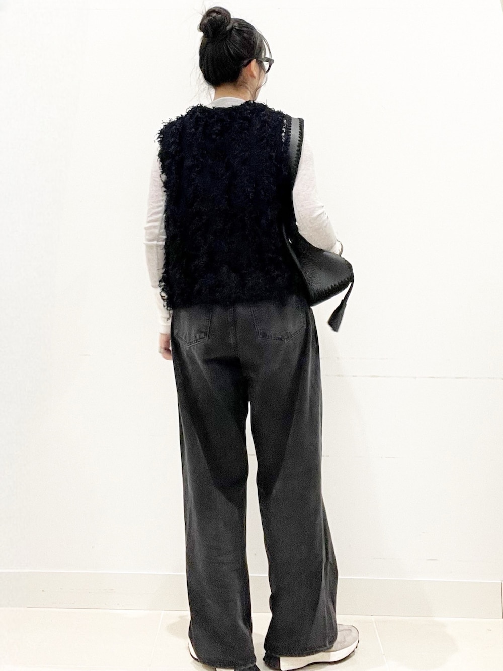ブラック系のデニムパンツ、ブラック系のショルダーバッグ、ブラック系のベストを着用したレディースの秋コーディネートの4枚目の写真