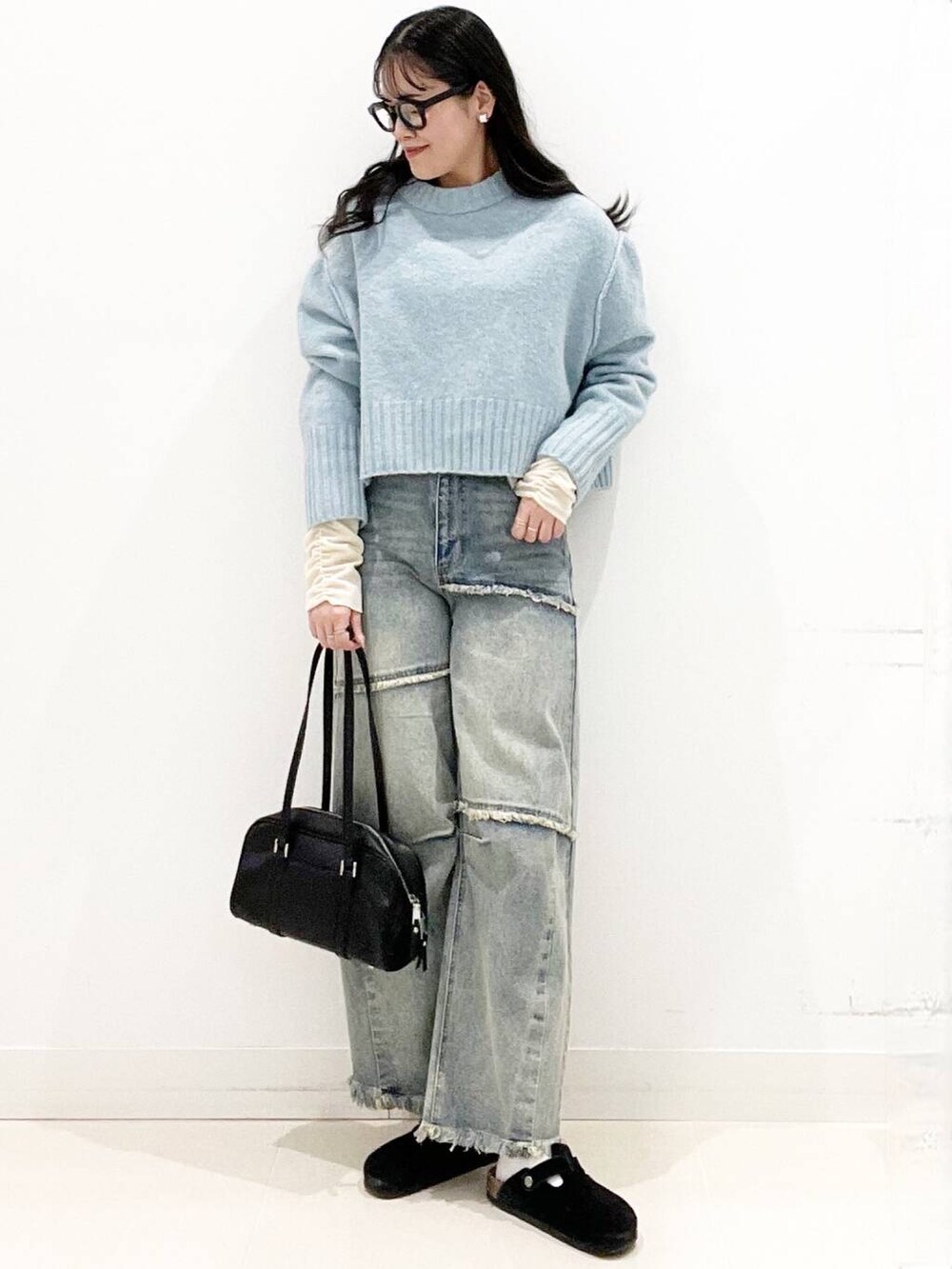 ブラック系のボストンバッグ、ブラック系のサンダル、ブルー系のニット/セーターを着用したレディースの冬コーディネートの2枚目の写真