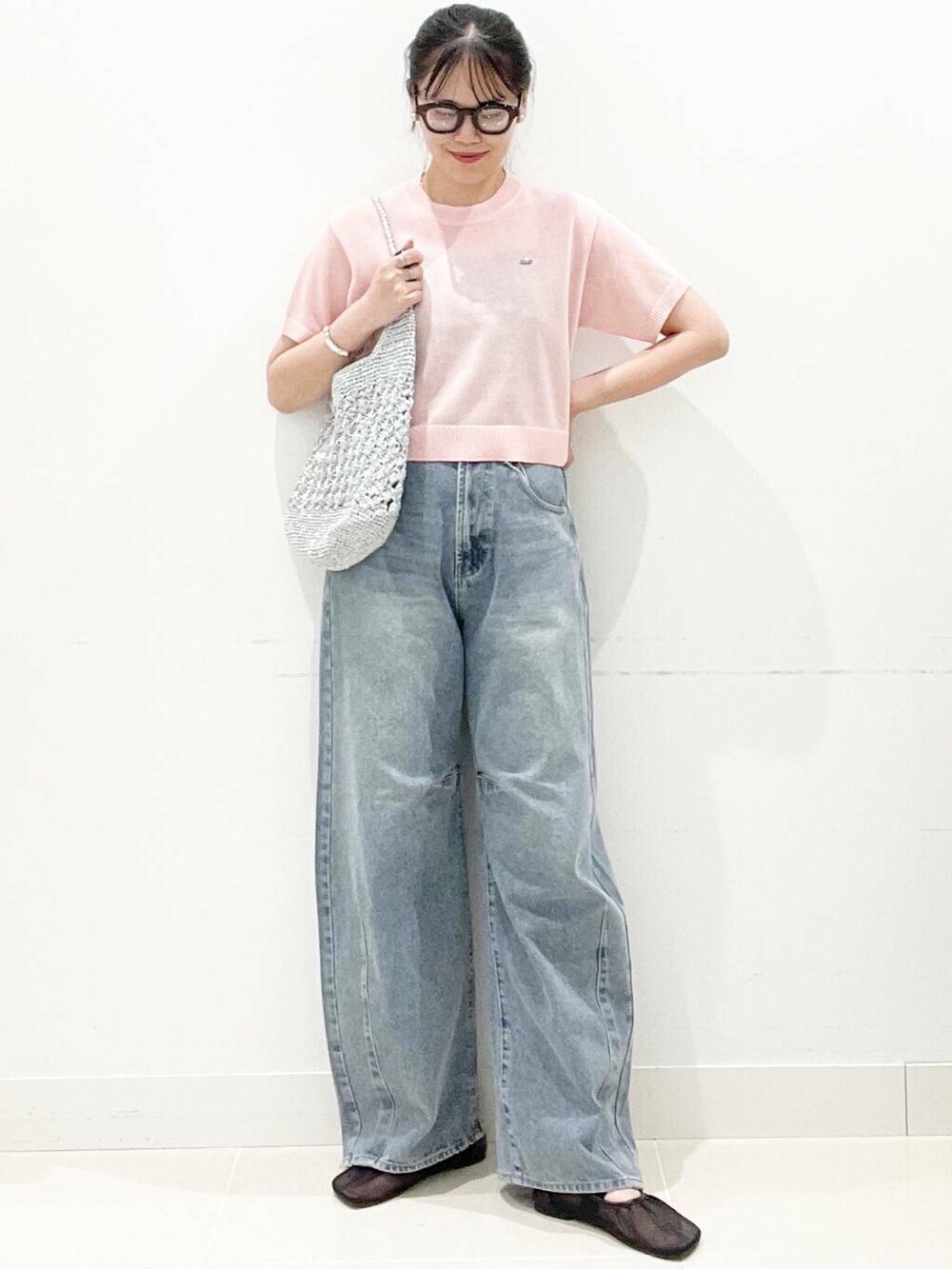 シルバー系のハンドバッグ、ブラック系のパンプス、ブルー系のデニムパンツを着用したレディースの夏コーディネートの3枚目の写真