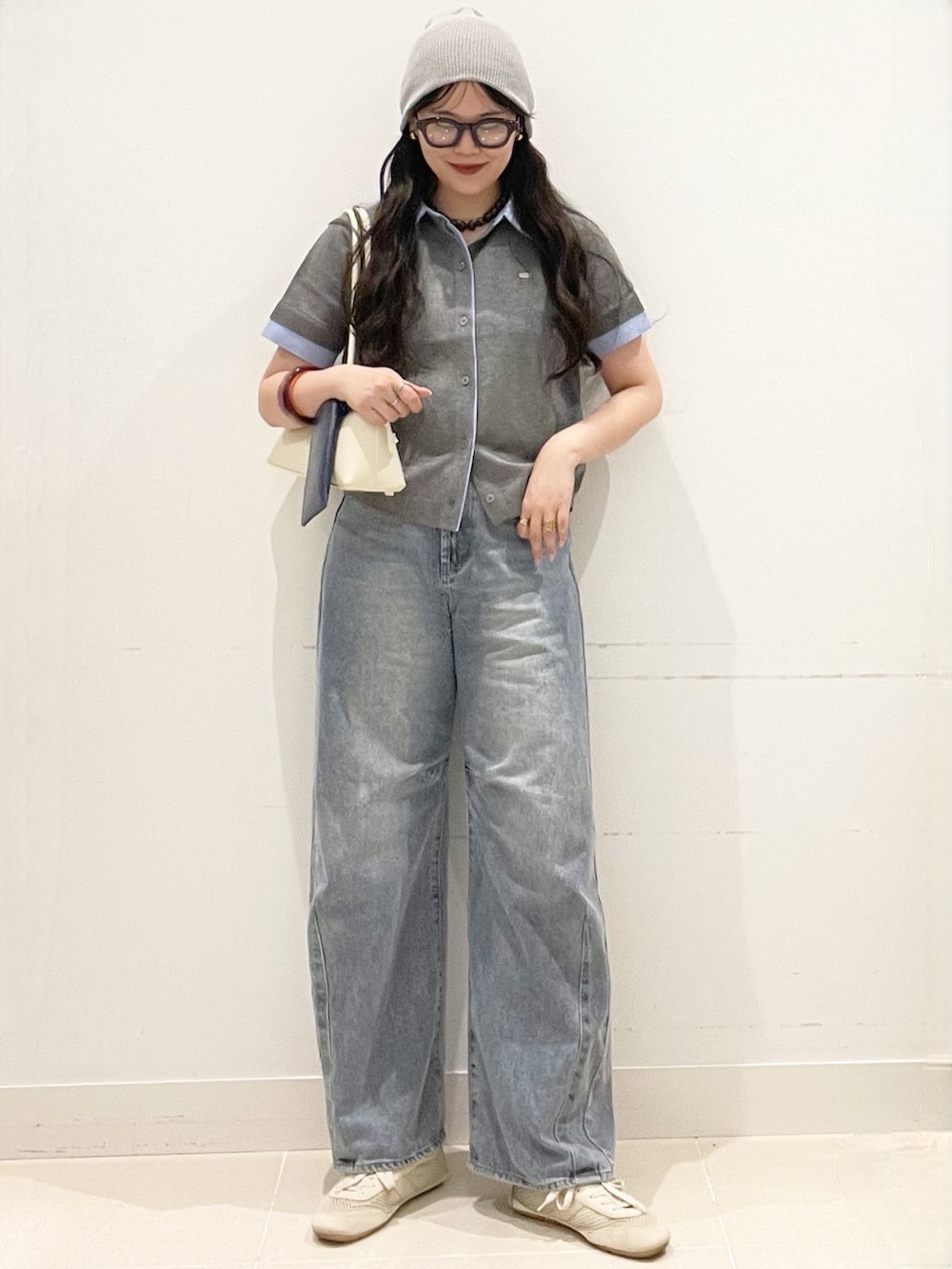 ブルー系のデニムパンツ、グレー系のカーディガン/ボレロ、ホワイト系のショルダーバッグを着用したレディースの春コーディネートの4枚目の写真
