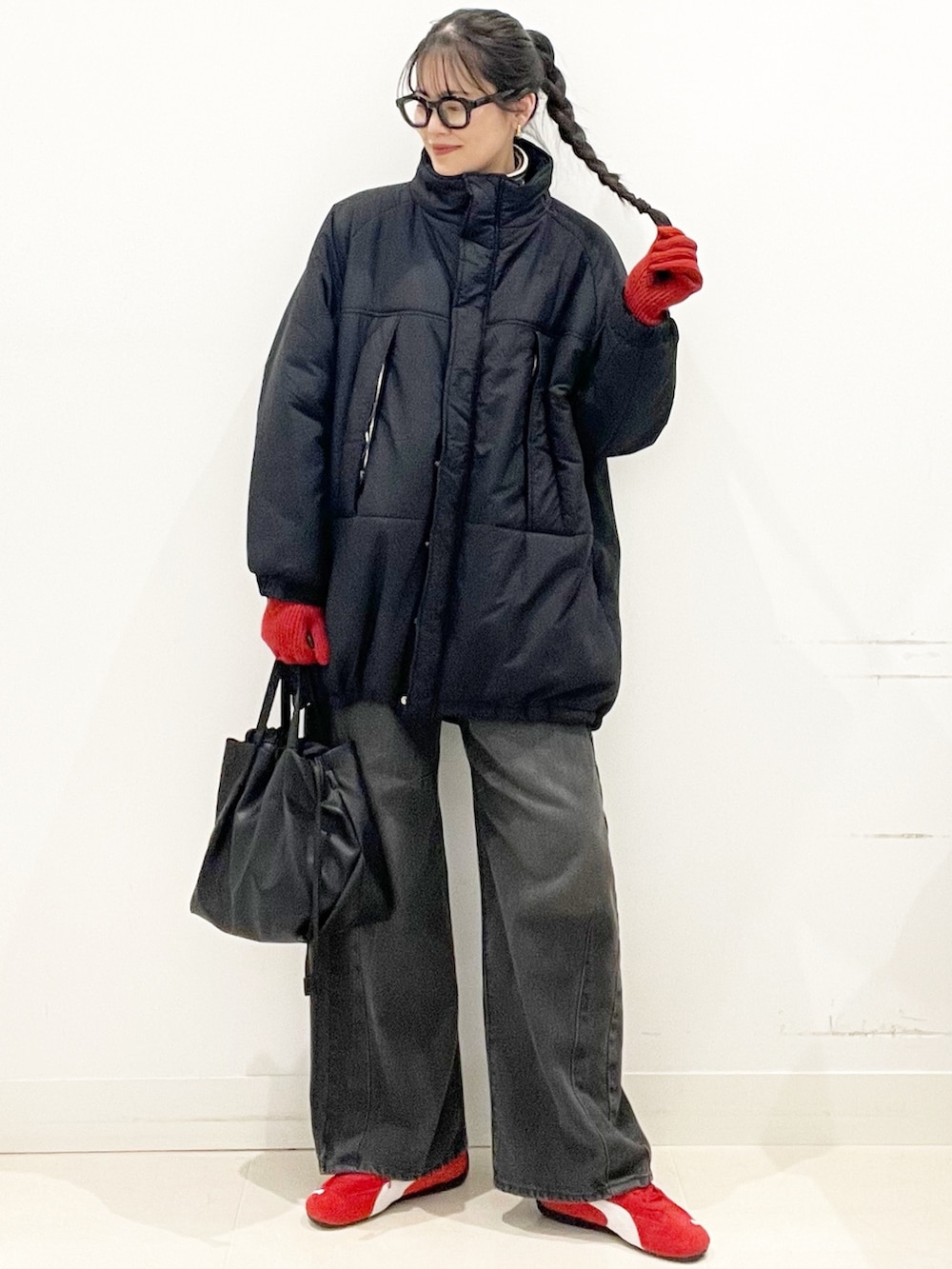 レッド系のスニーカー、ブラック系のダウンジャケット/コート、グレー系のデニムパンツを着用したレディースの冬コーディネートの3枚目の写真