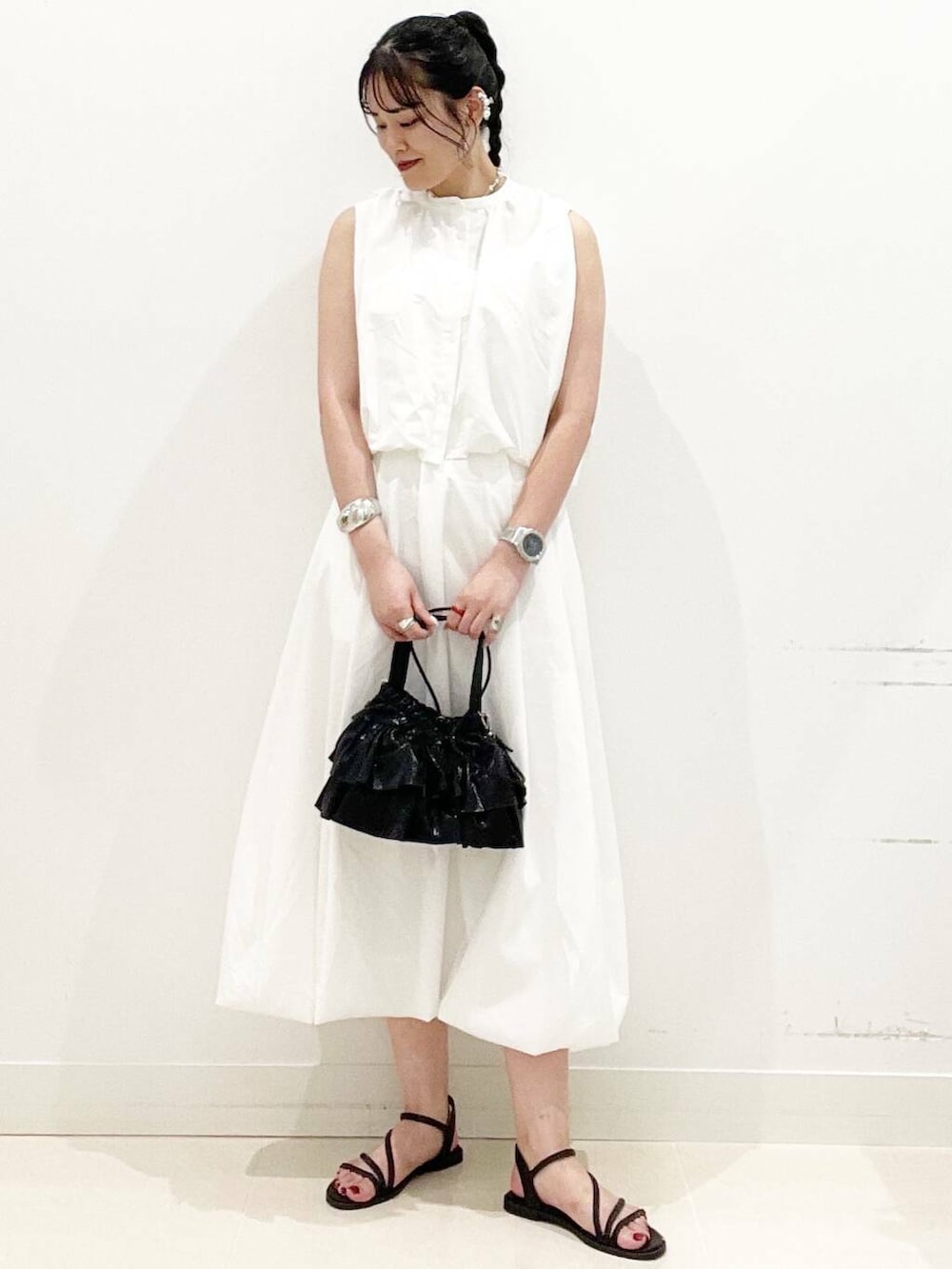 ブラック系のショルダーバッグ、ホワイト系のスカート、ホワイト系のキャミソールを着用したレディースの夏コーディネートの4枚目の写真