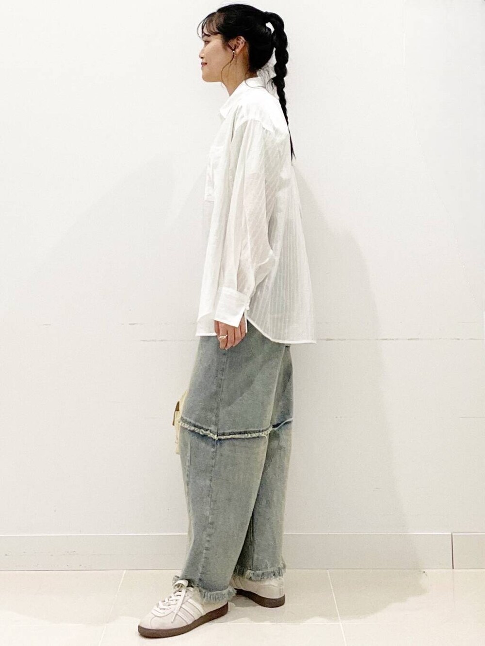 ホワイト系のスニーカー、ブルー系のデニムパンツ、ベージュ系のショルダーバッグを着用したレディースの春コーディネートの3枚目の写真