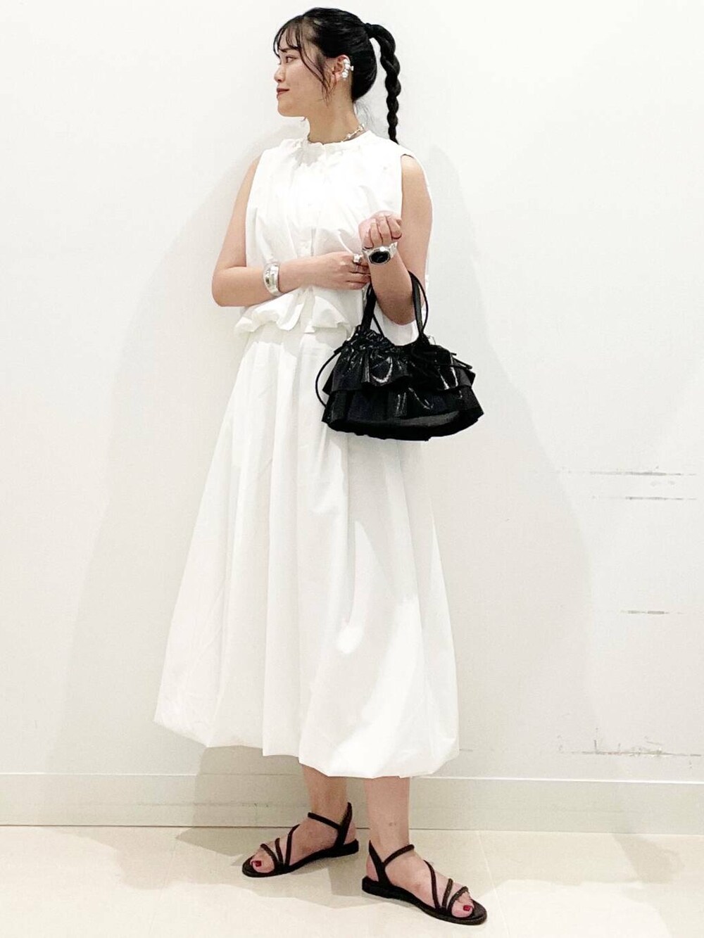 ブラック系のショルダーバッグ、ホワイト系のスカート、ホワイト系のキャミソールを着用したレディースの夏コーディネートの3枚目の写真