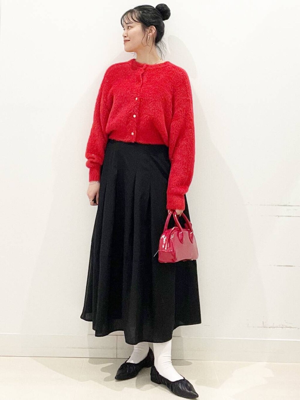 レッド系のボストンバッグ、レッド系のニット/セーター、ブラック系のバレエシューズを着用したレディースの冬コーディネートの4枚目の写真