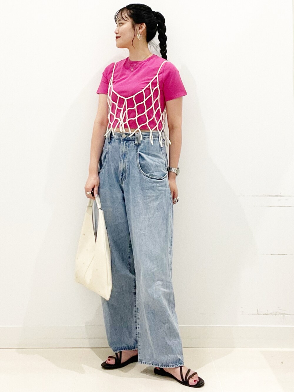 ブルー系のデニムパンツ、ブラック系のサンダル、ホワイト系のトートバッグを着用したレディースの夏コーディネートの3枚目の写真