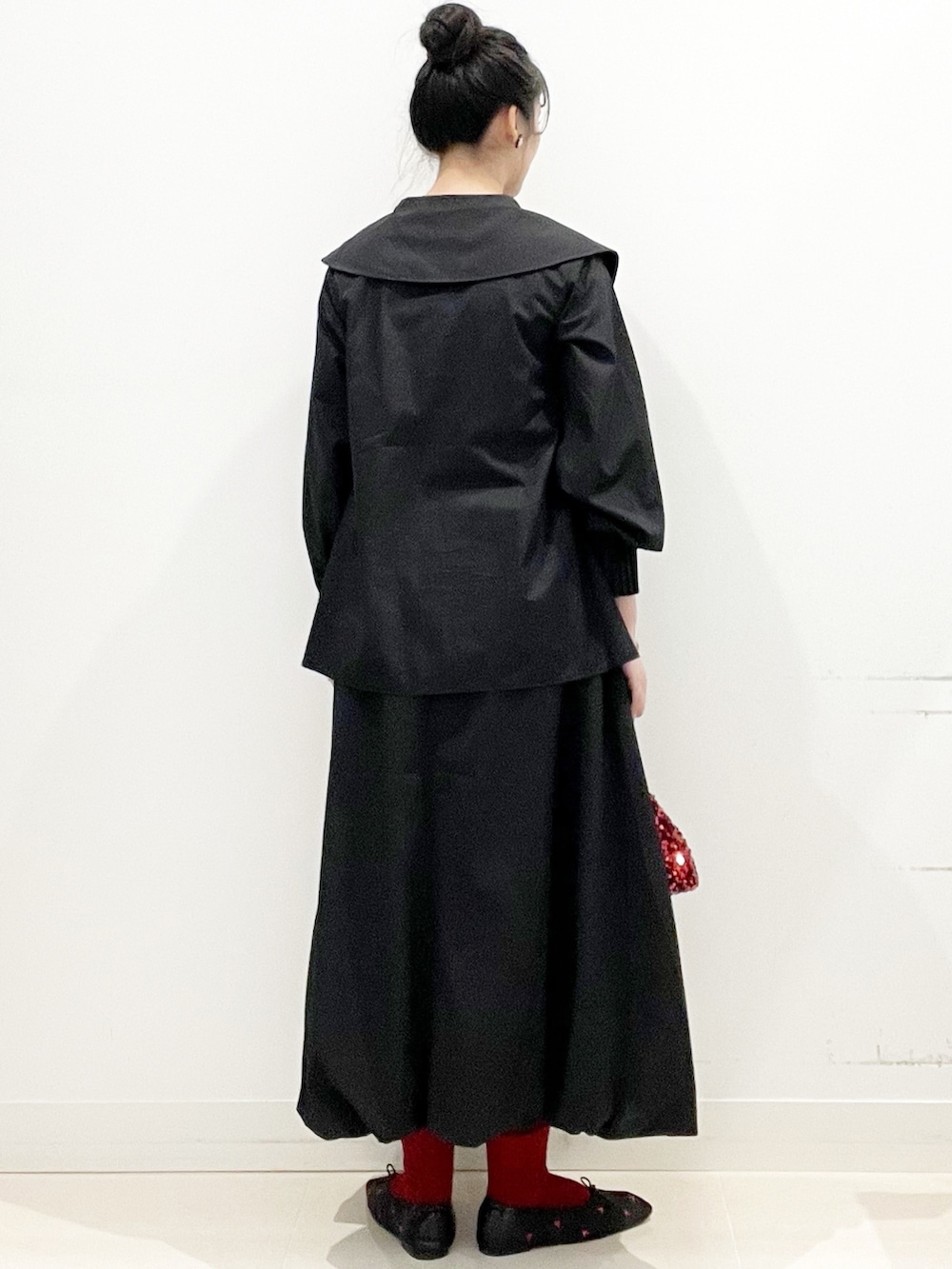 ブラック系のバレエシューズ、ブラック系のスカート、レッド系のショルダーバッグを着用したレディースの秋コーディネートの6枚目の写真