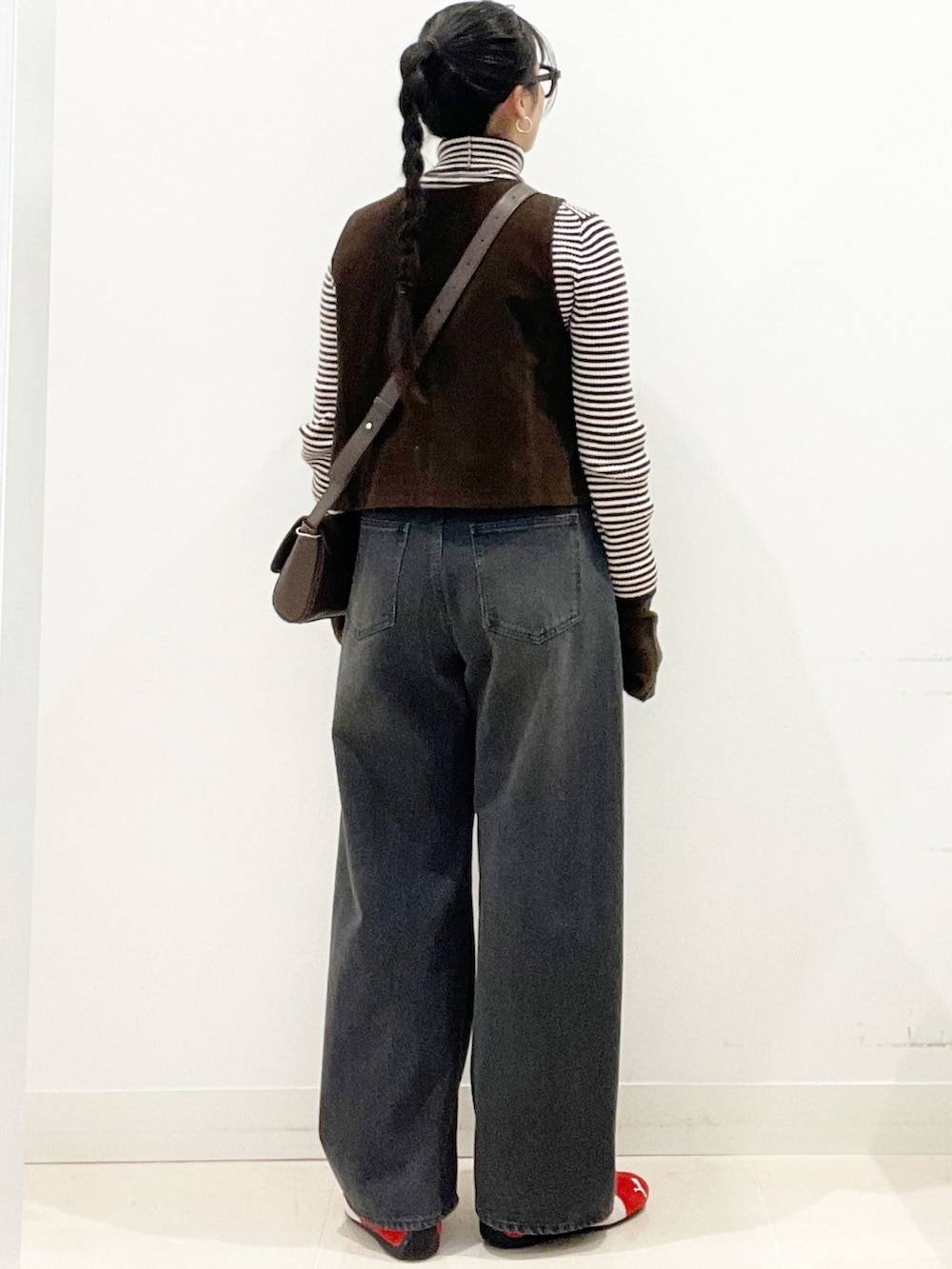 レッド系のスニーカー、グレー系のデニムパンツ、ブラウン系のショルダーバッグを着用したレディースの冬コーディネートの6枚目の写真