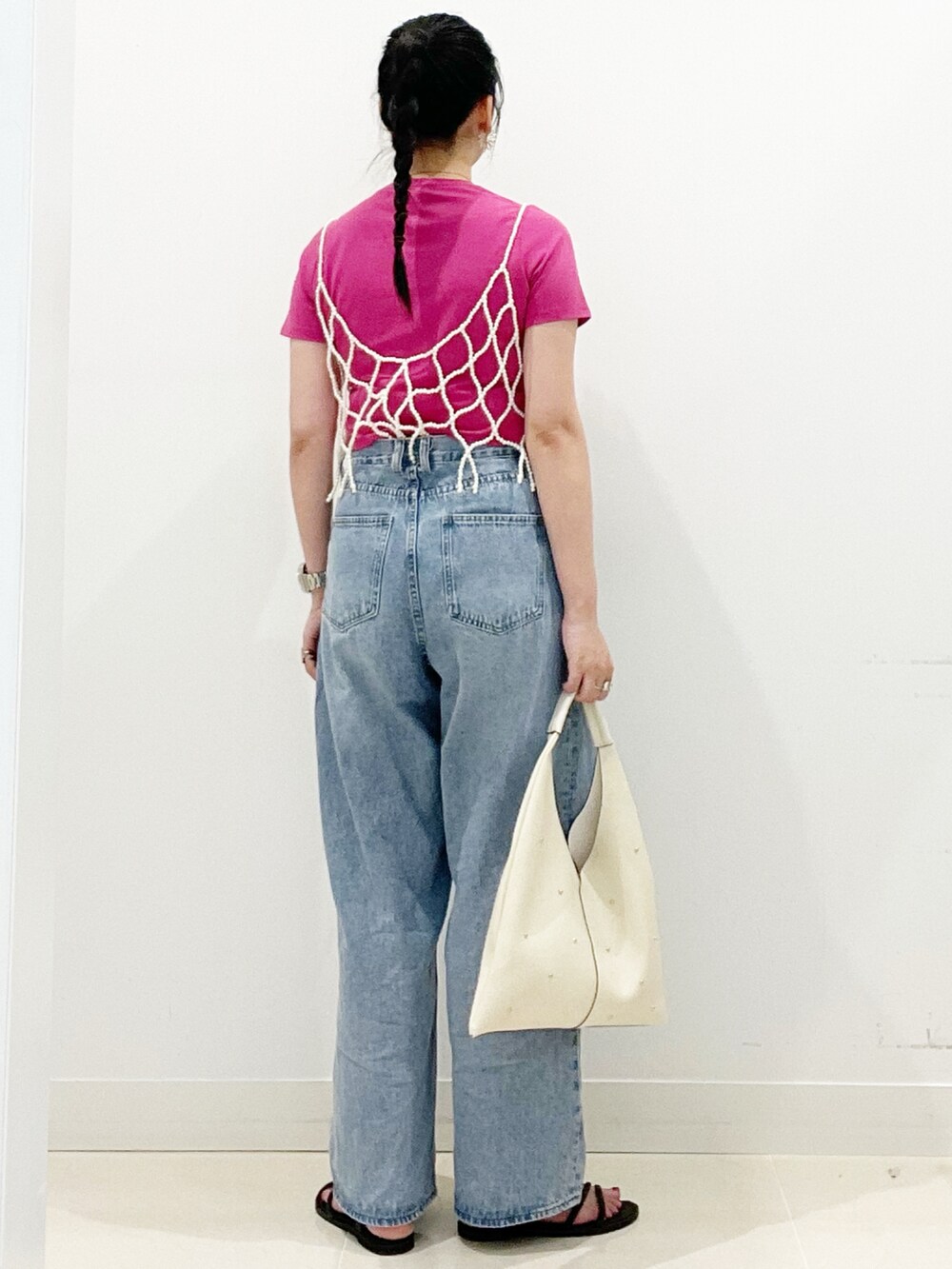 ブルー系のデニムパンツ、ブラック系のサンダル、ホワイト系のトートバッグを着用したレディースの夏コーディネートの7枚目の写真