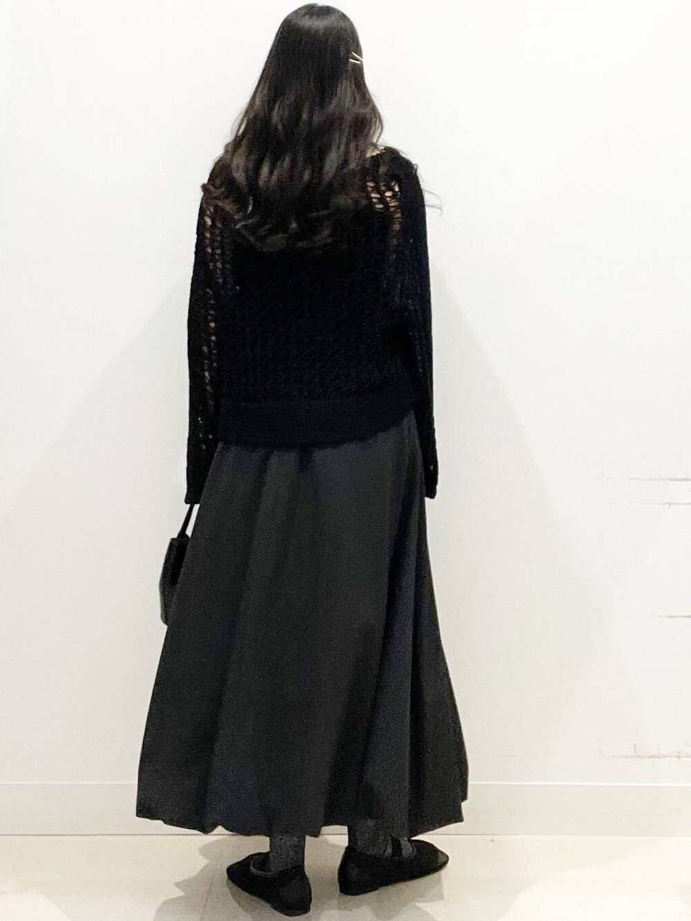 ブラック系のショルダーバッグ、ブラック系のスカート、ブラック系のニット/セーターを着用したレディースの春コーディネートの5枚目の写真