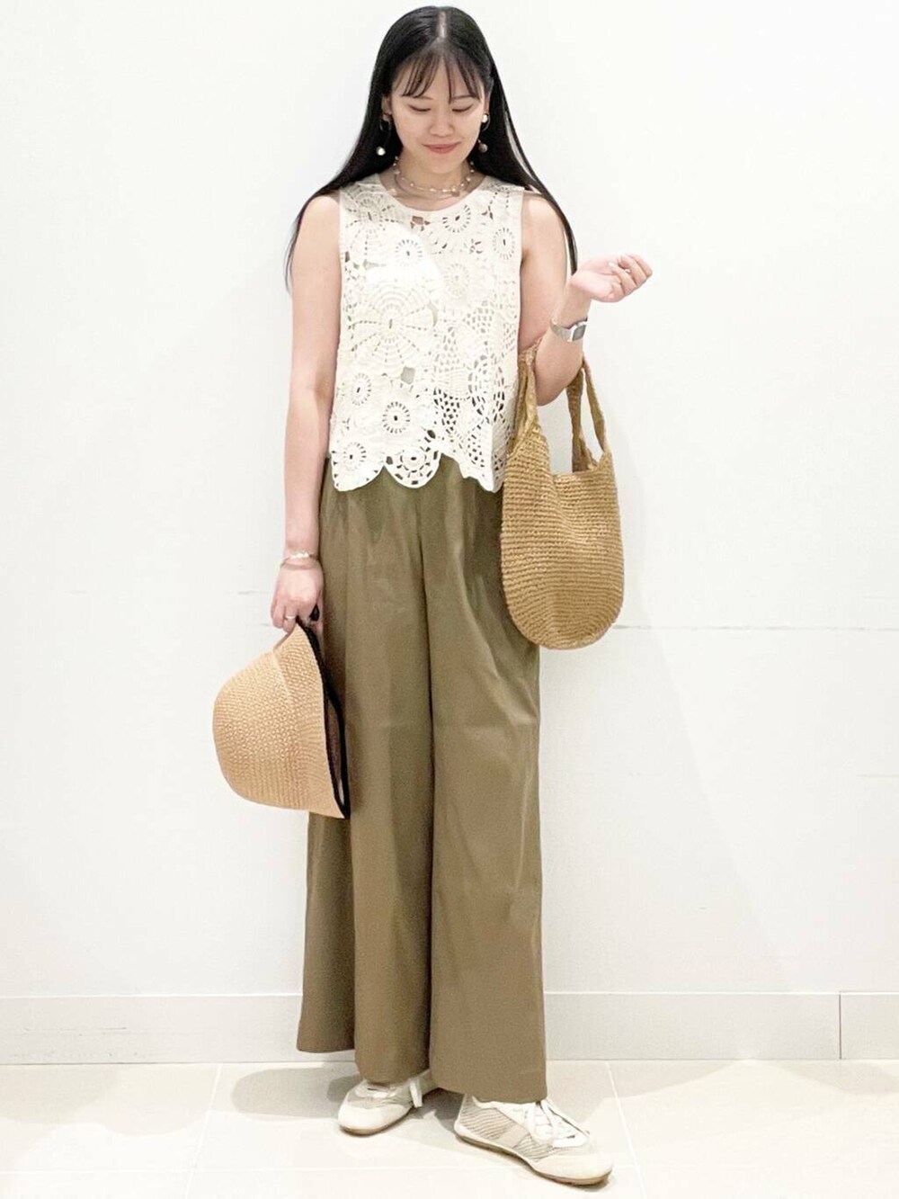 イエロー系のトートバッグ、ホワイト系のキャミソール、ホワイト系のベストを着用したレディースの夏コーディネートの5枚目の写真