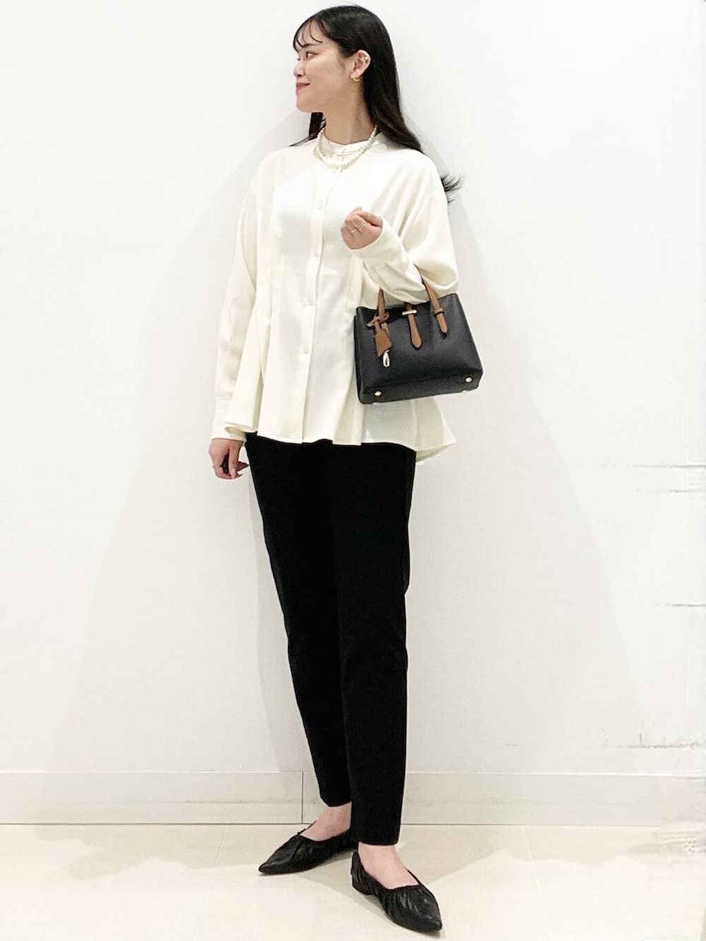 ブラック系のハンドバッグ、ブラック系のバレエシューズ、ホワイト系のシャツ/ブラウスを着用したレディースの冬コーディネートの2枚目の写真