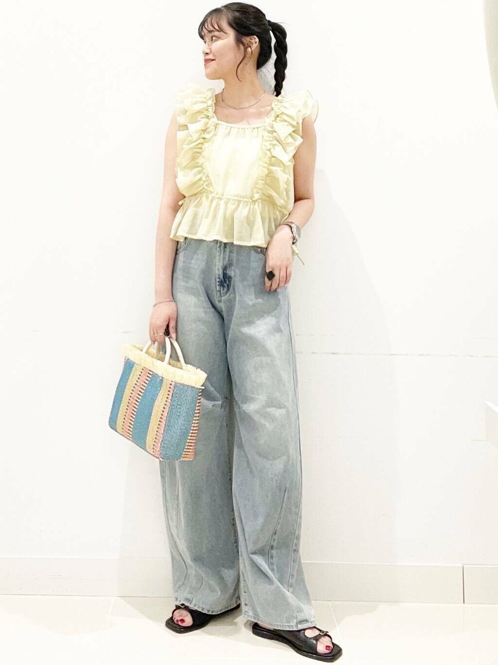 ホワイト系のキャミソール、ブルー系のデニムパンツ、ベージュ系のショルダーバッグを着用したレディースの夏コーディネートの2枚目の写真