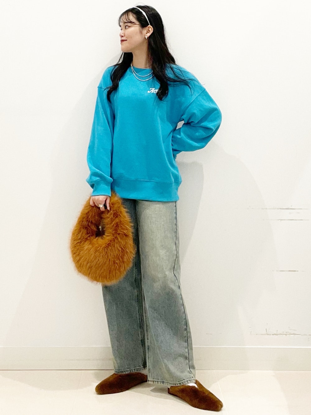 ブラウン系のハンドバッグ、イエロー系のその他シューズ、ブルー系のデニムパンツを着用したレディースの秋コーディネートの2枚目の写真