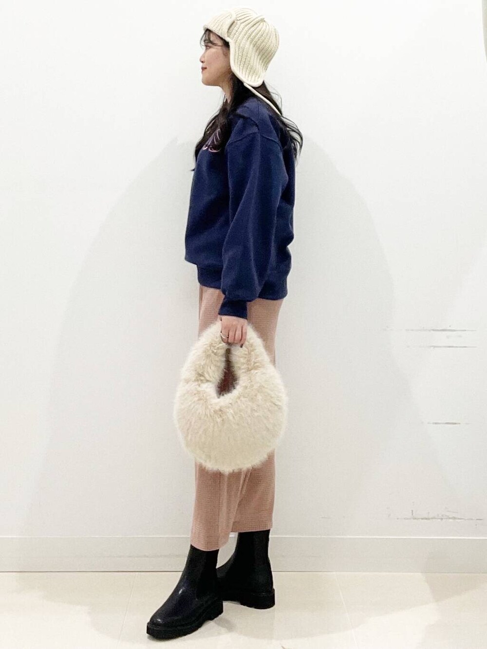 ベージュ系のハンドバッグ、ブラック系のブーツ、ピンク系のスカートを着用したレディースの秋コーディネートの6枚目の写真