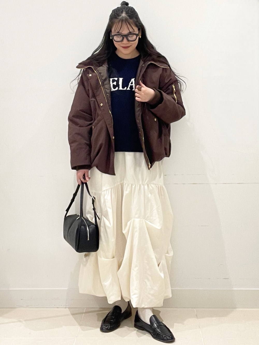 ホワイト系のスカート、ブラック系のボストンバッグ、ブルー系のニット/セーターを着用したレディースの冬コーディネートの3枚目の写真