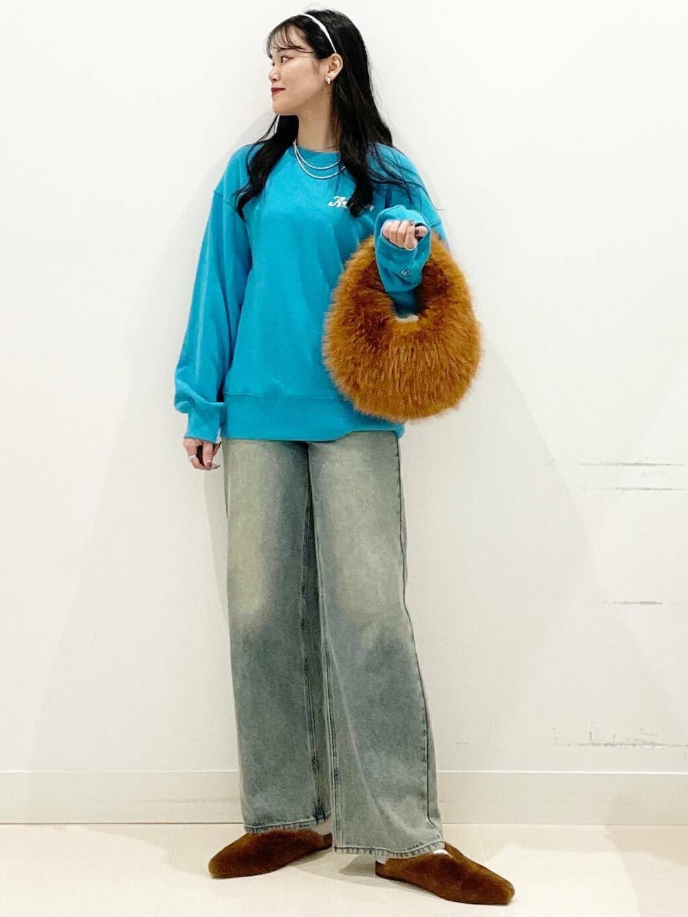 ブラウン系のハンドバッグ、イエロー系のその他シューズ、ブルー系のデニムパンツを着用したレディースの秋コーディネートの3枚目の写真