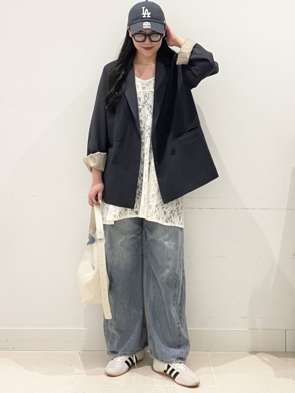 ホワイト系のスニーカー、ブルー系のデニムパンツ、ホワイト系のキャミソールを着用したレディースの春コーディネートの3枚目の写真