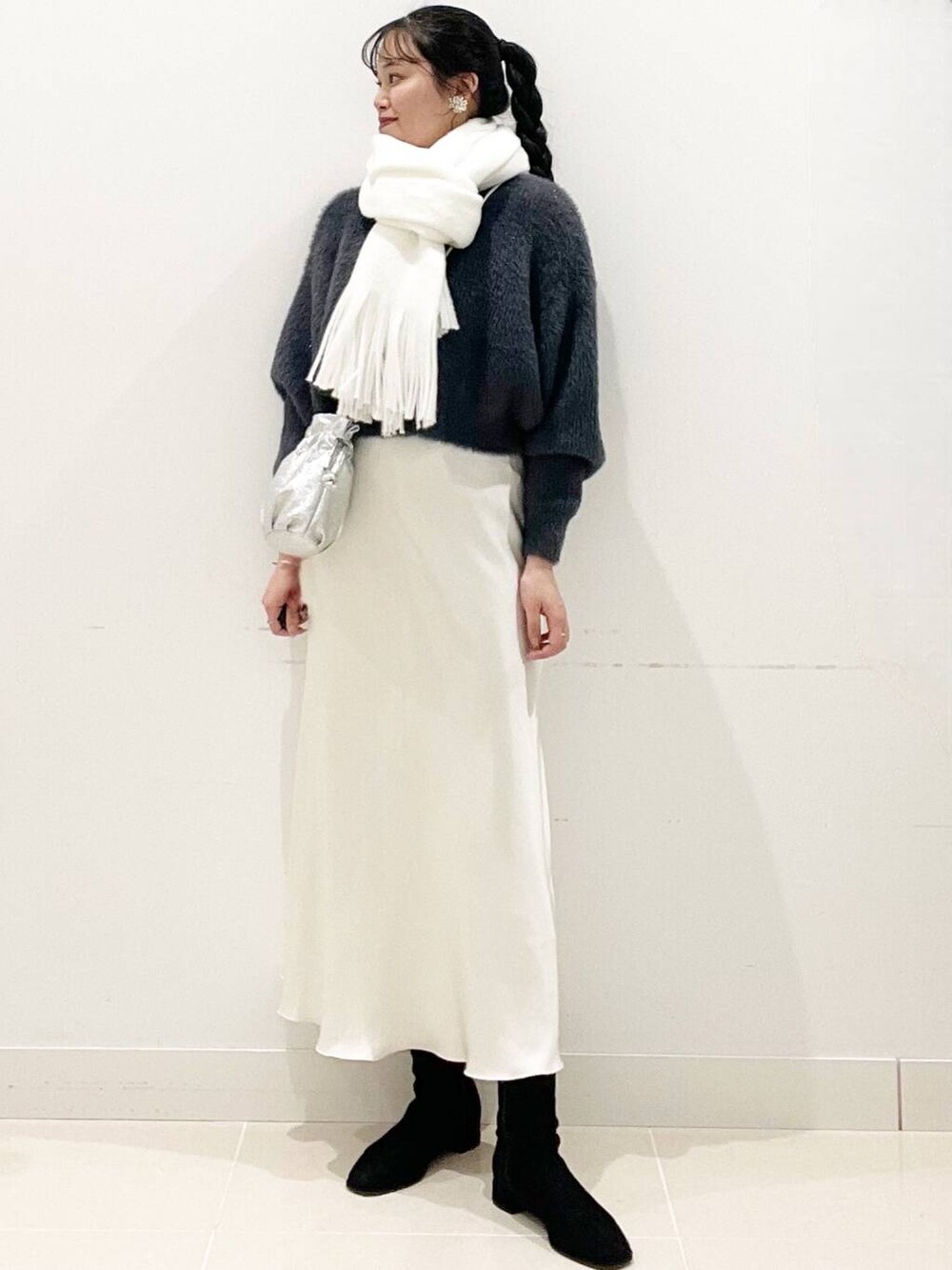 グレー系のニット/セーター、ブラック系のブーツ、シルバー系のショルダーバッグを着用したレディースの冬コーディネートの2枚目の写真