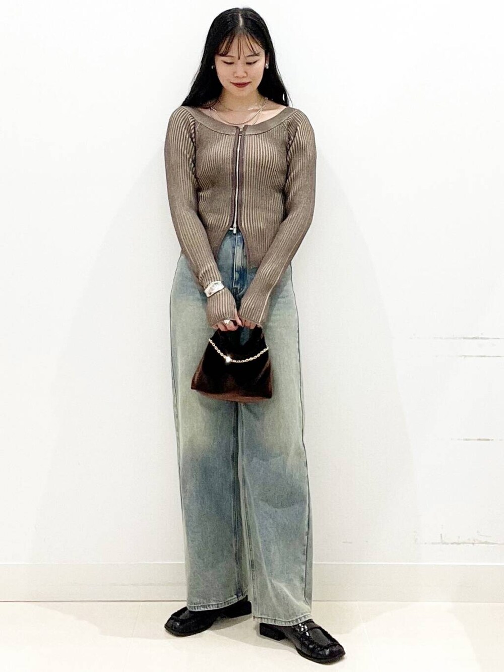 ブラウン系のハンドバッグ、ブラック系のローファー、ブラウン系のニット/セーターを着用したレディースの秋コーディネートの4枚目の写真