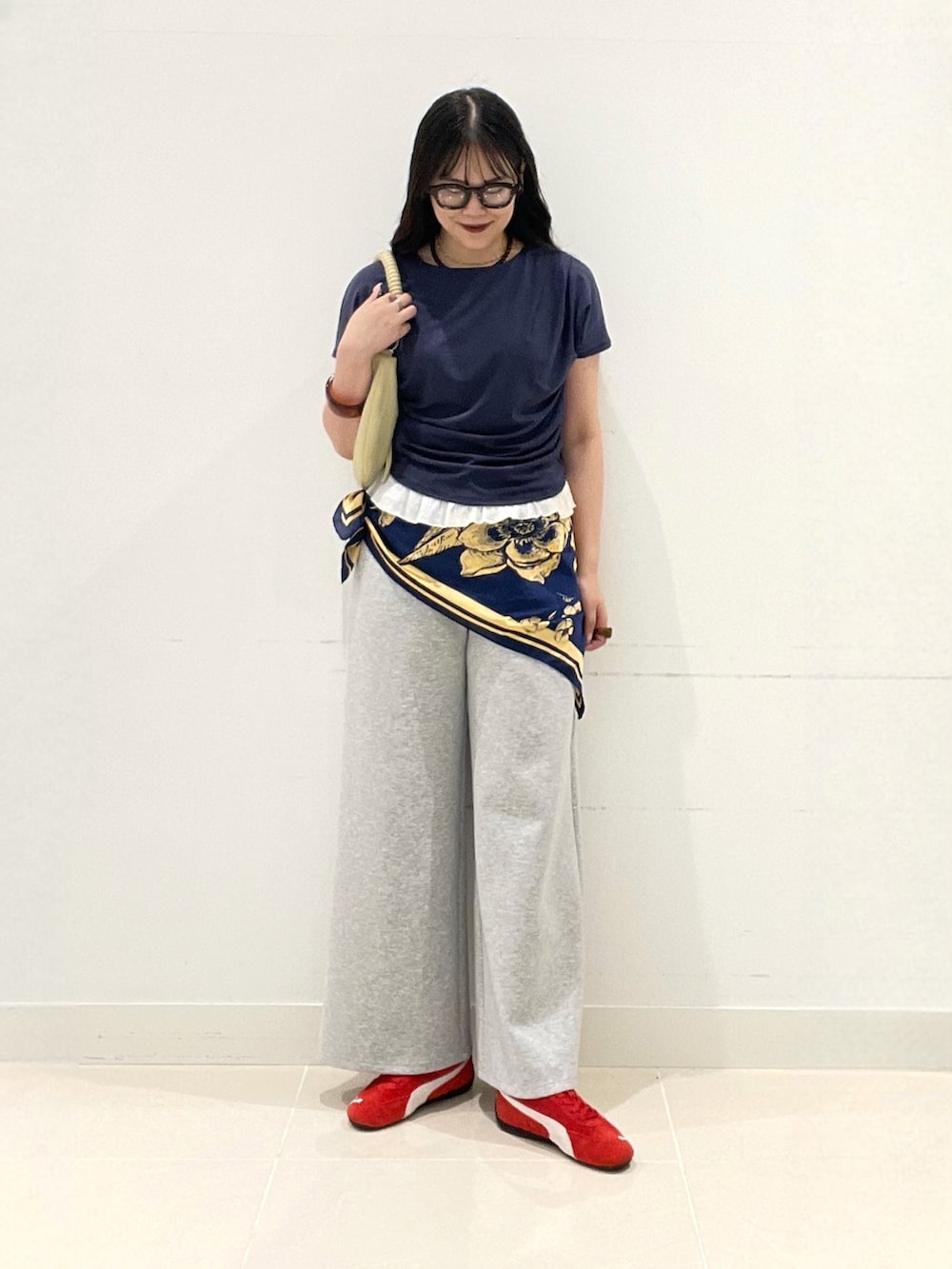 グレー系のスラックス、レッド系のスニーカー、ベージュ系のハンドバッグを着用したレディースの夏コーディネートの3枚目の写真