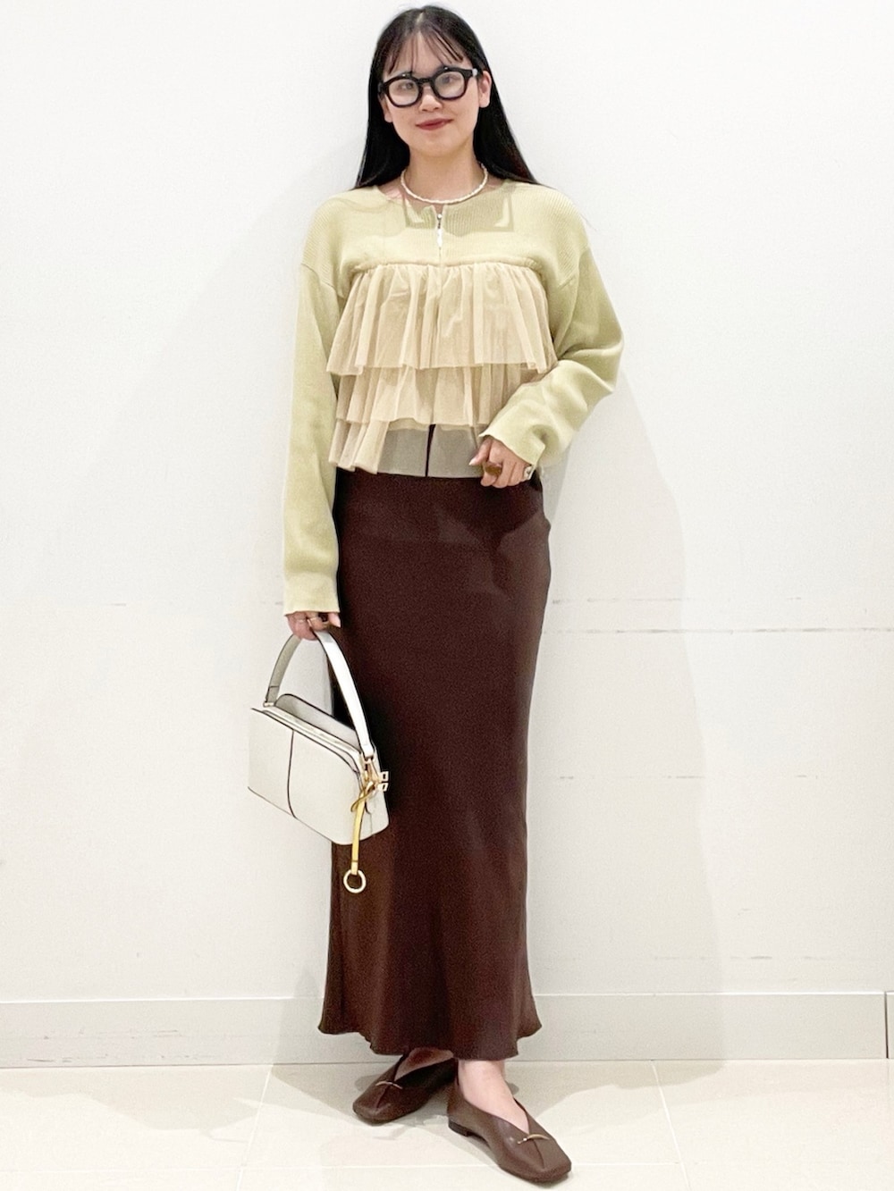 ブラウン系のその他シューズ、ホワイト系のショルダーバッグ、ベージュ系のニット/セーターを着用したレディースの春コーディネートの2枚目の写真