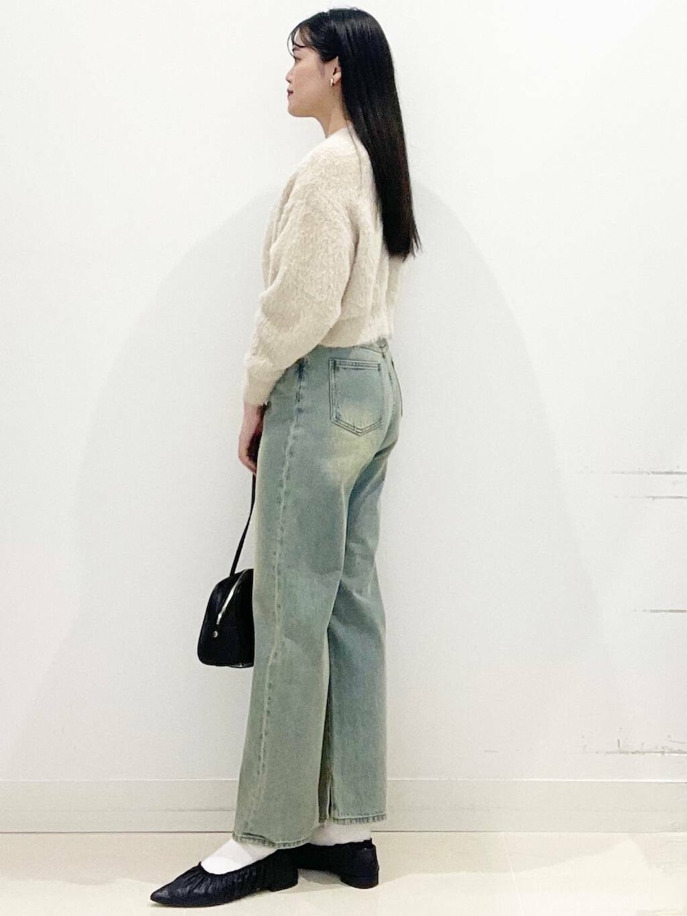 ベージュ系のニット/セーター、ブラック系のボストンバッグ、ブルー系のデニムパンツを着用したレディースの冬コーディネートの5枚目の写真