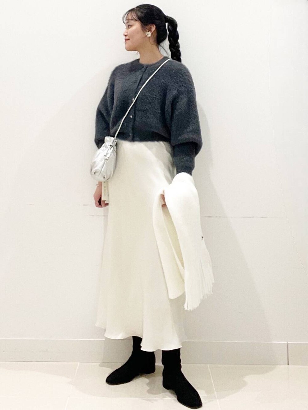 グレー系のニット/セーター、ブラック系のブーツ、シルバー系のショルダーバッグを着用したレディースの冬コーディネートの3枚目の写真