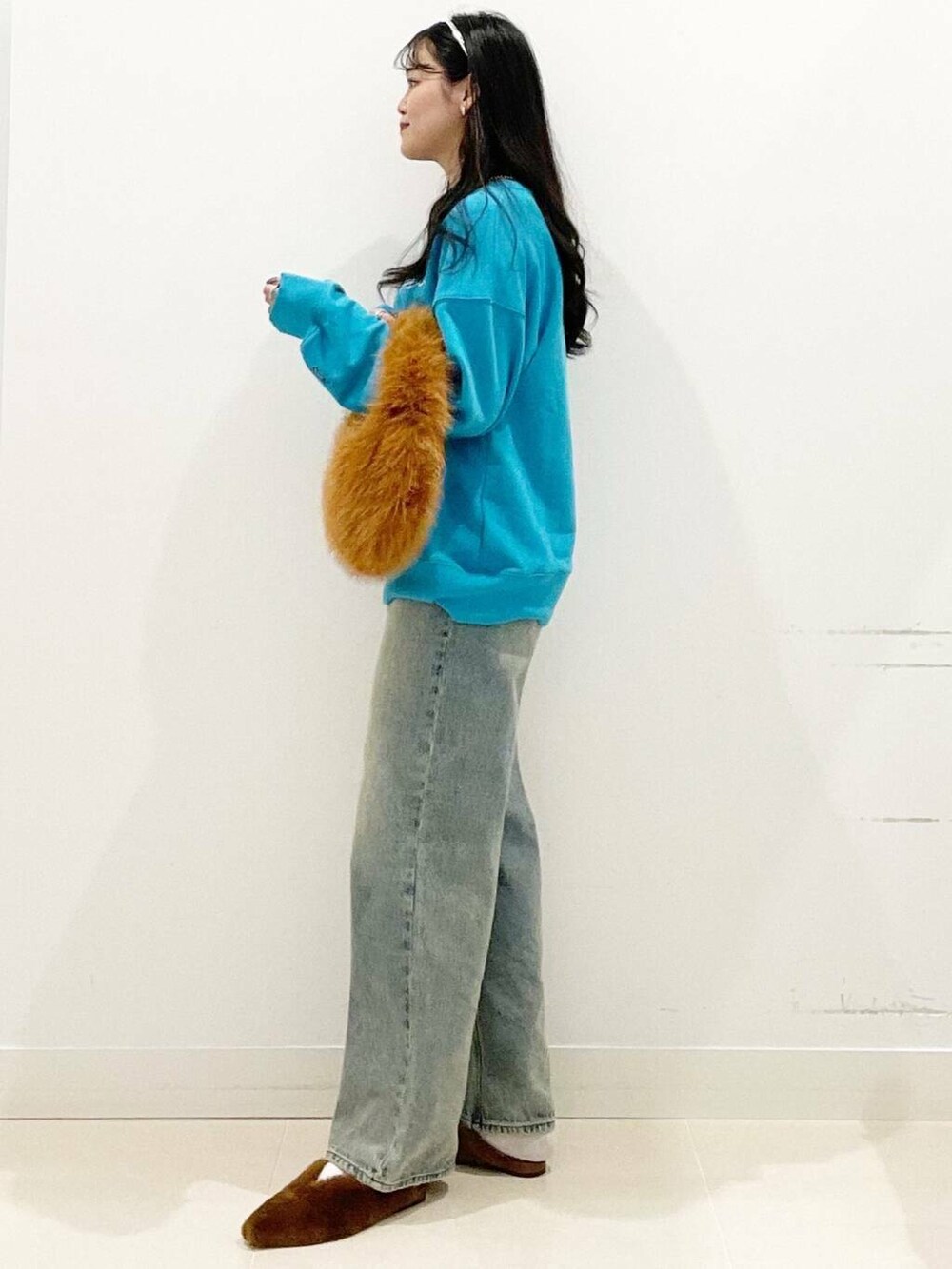 ブラウン系のハンドバッグ、イエロー系のその他シューズ、ブルー系のデニムパンツを着用したレディースの秋コーディネートの5枚目の写真