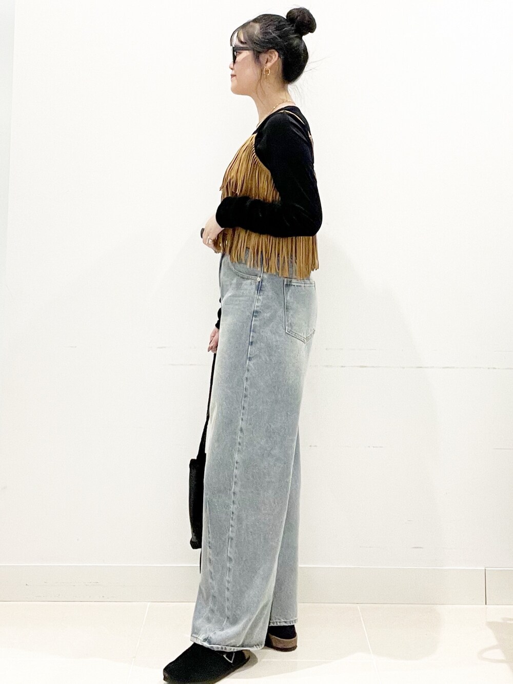 ブラック系のサンダル、ブラック系のショルダーバッグ、ブルー系のデニムパンツを着用したレディースの秋コーディネートの5枚目の写真