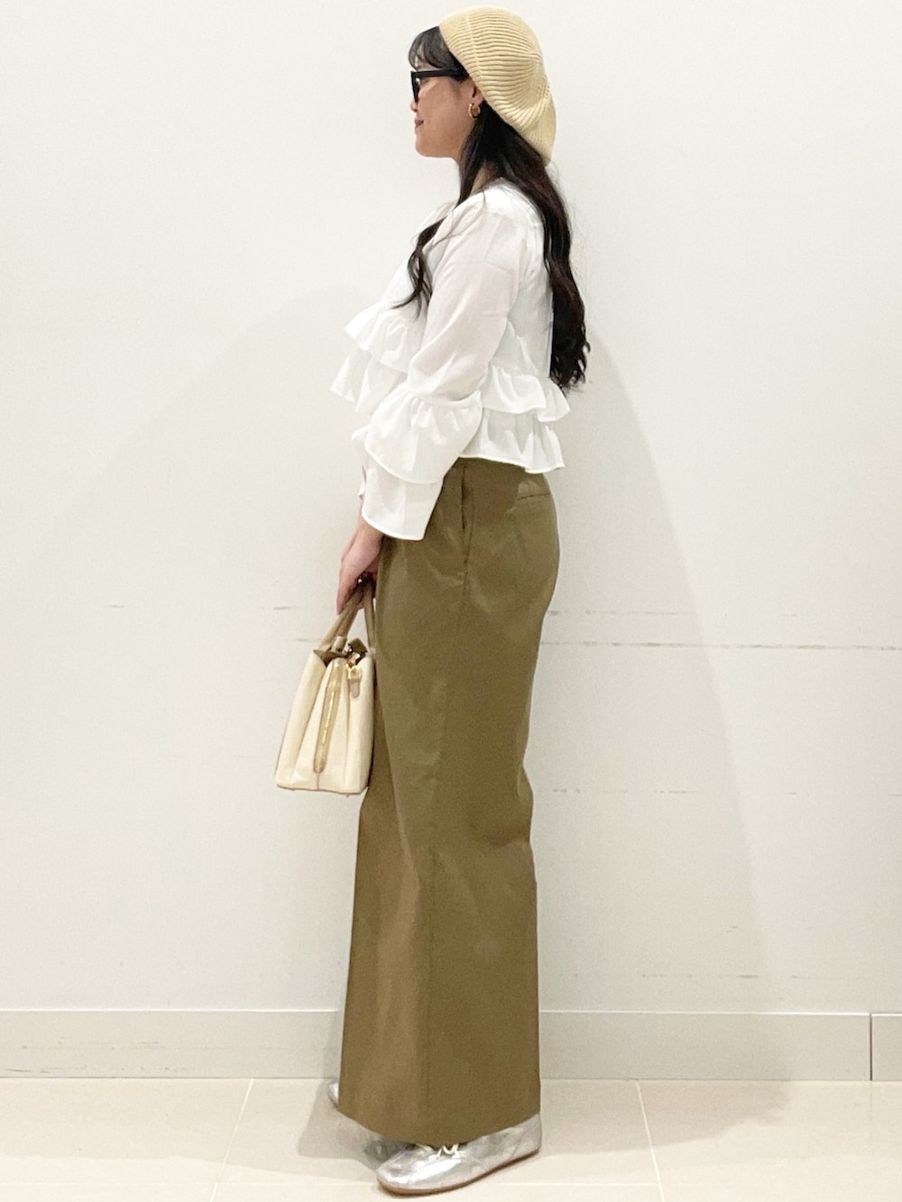 ベージュ系のチノパンツ、ホワイト系のハンドバッグ、ホワイト系のキャミソールを着用したレディースの春コーディネートの5枚目の写真