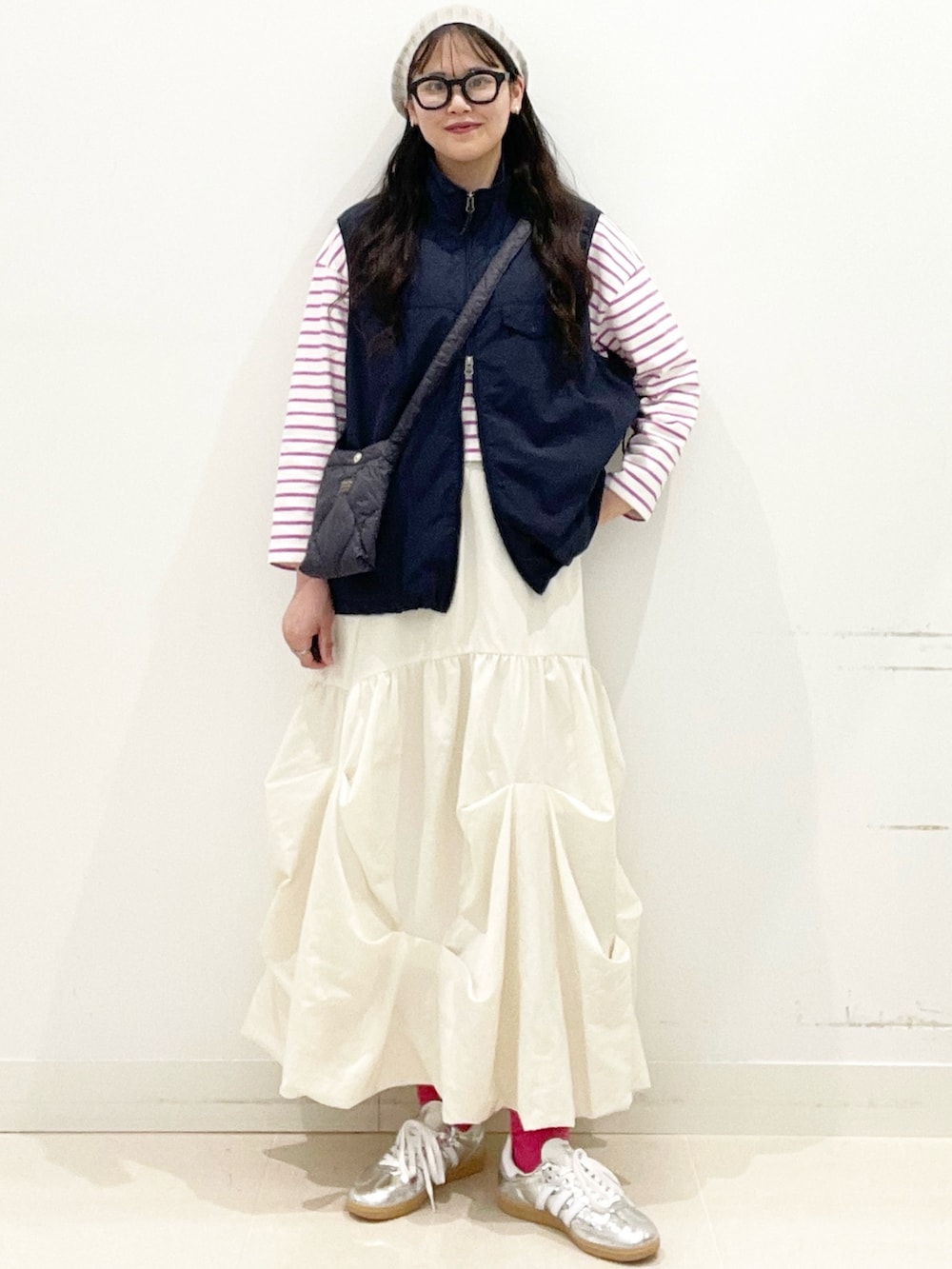 シルバー系のスニーカー、ホワイト系のスカート、ブルー系のナイロンジャケットを着用したレディースの春コーディネートの3枚目の写真