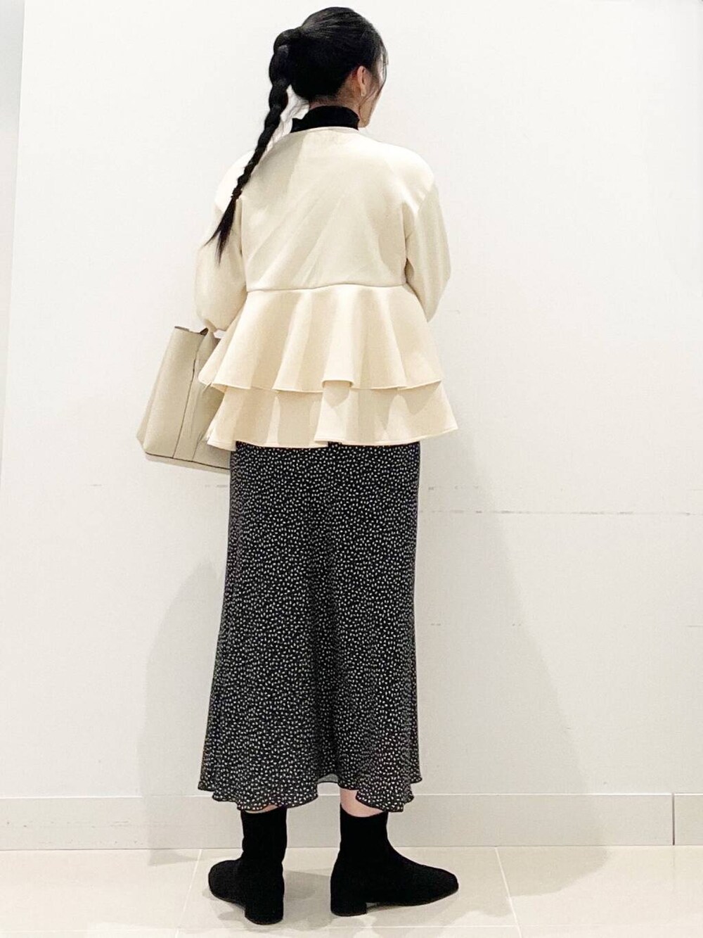 ブラック系のニット/セーター、ブラック系のブーツ、ホワイト系のトートバッグを着用したレディースの冬コーディネートの6枚目の写真