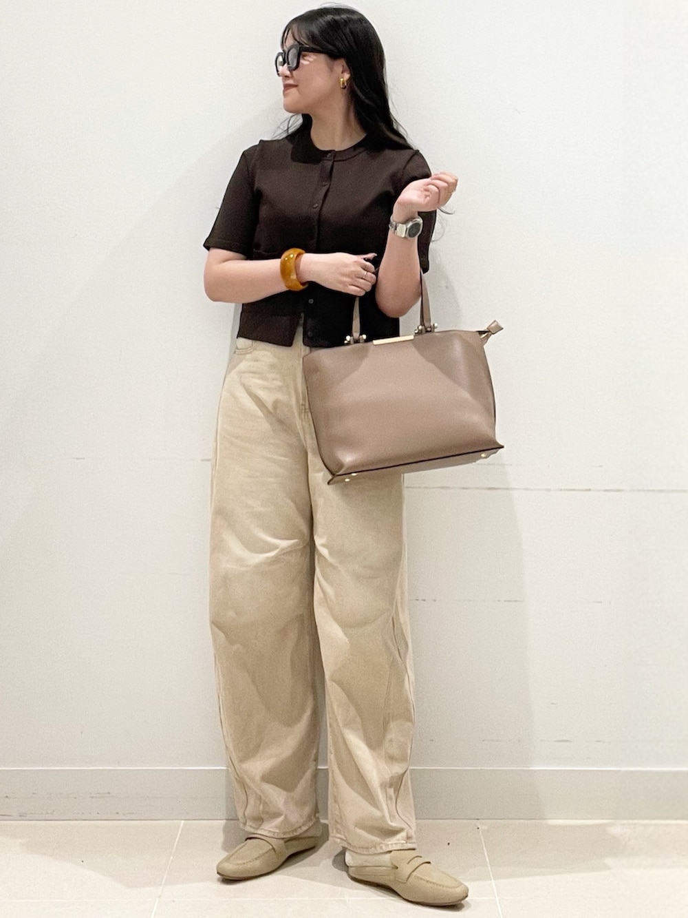 ブラウン系のカーディガン/ボレロ、ベージュ系のデニムパンツ、ブラウン系のビジネスバッグを着用したレディースの春コーディネートの3枚目の写真