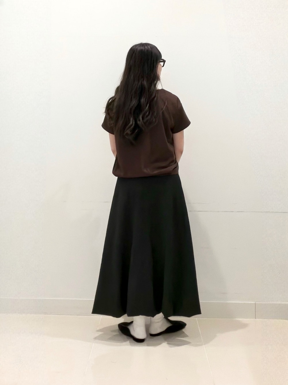 ブラウン系のTシャツ/カットソー、ブラック系のスカート、ブラック系のトートバッグを着用したレディースの秋コーディネートの5枚目の写真