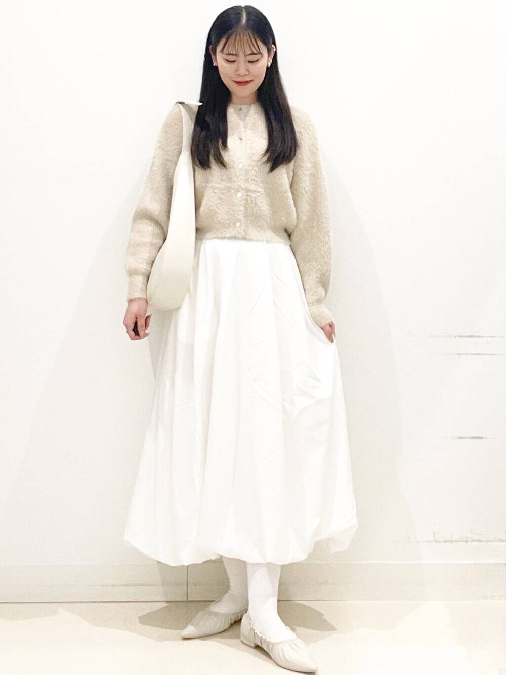 ホワイト系のスカート、ベージュ系のニット/セーター、ホワイト系のショルダーバッグを着用したレディースの冬コーディネートの3枚目の写真